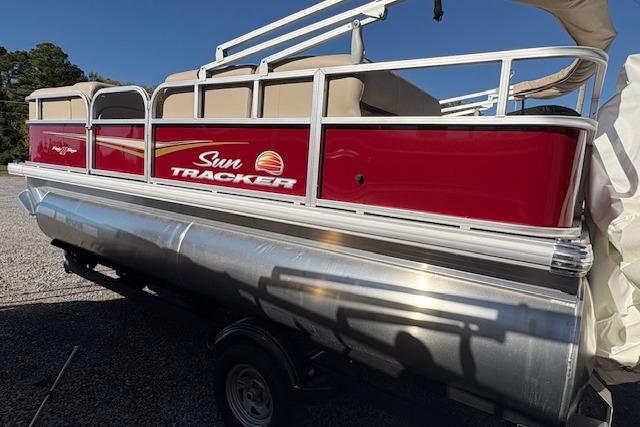 2025 Sun Tracker Party Barge 18 DLX pontoon boat with red exterior on a trailer.