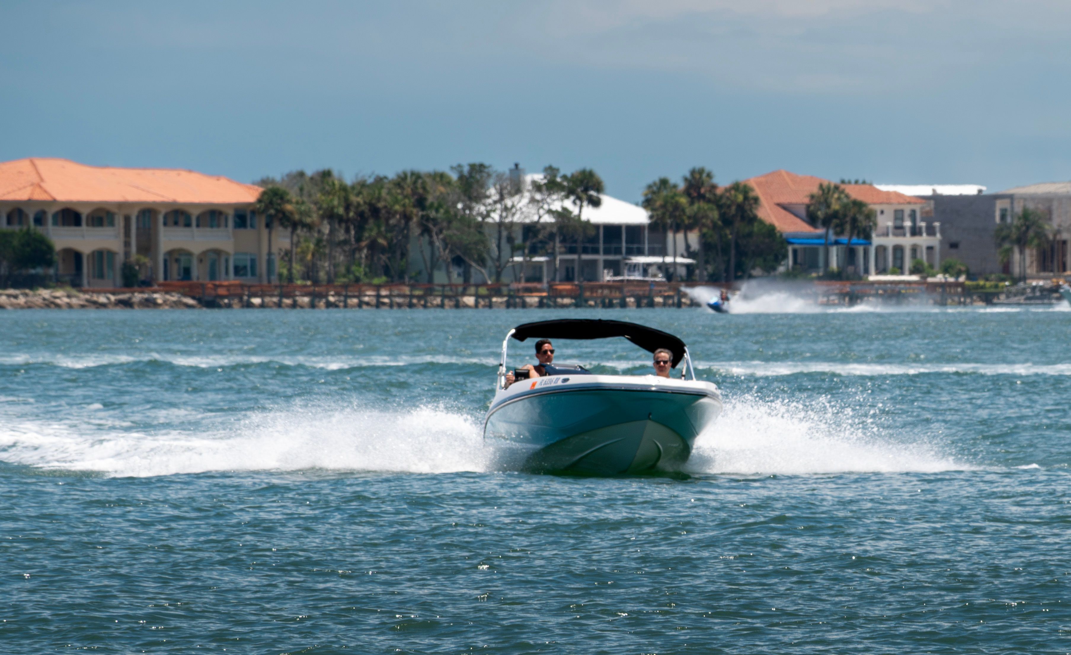A 2018 Scarab 165 ID cruising on the water, with houses in the background.
