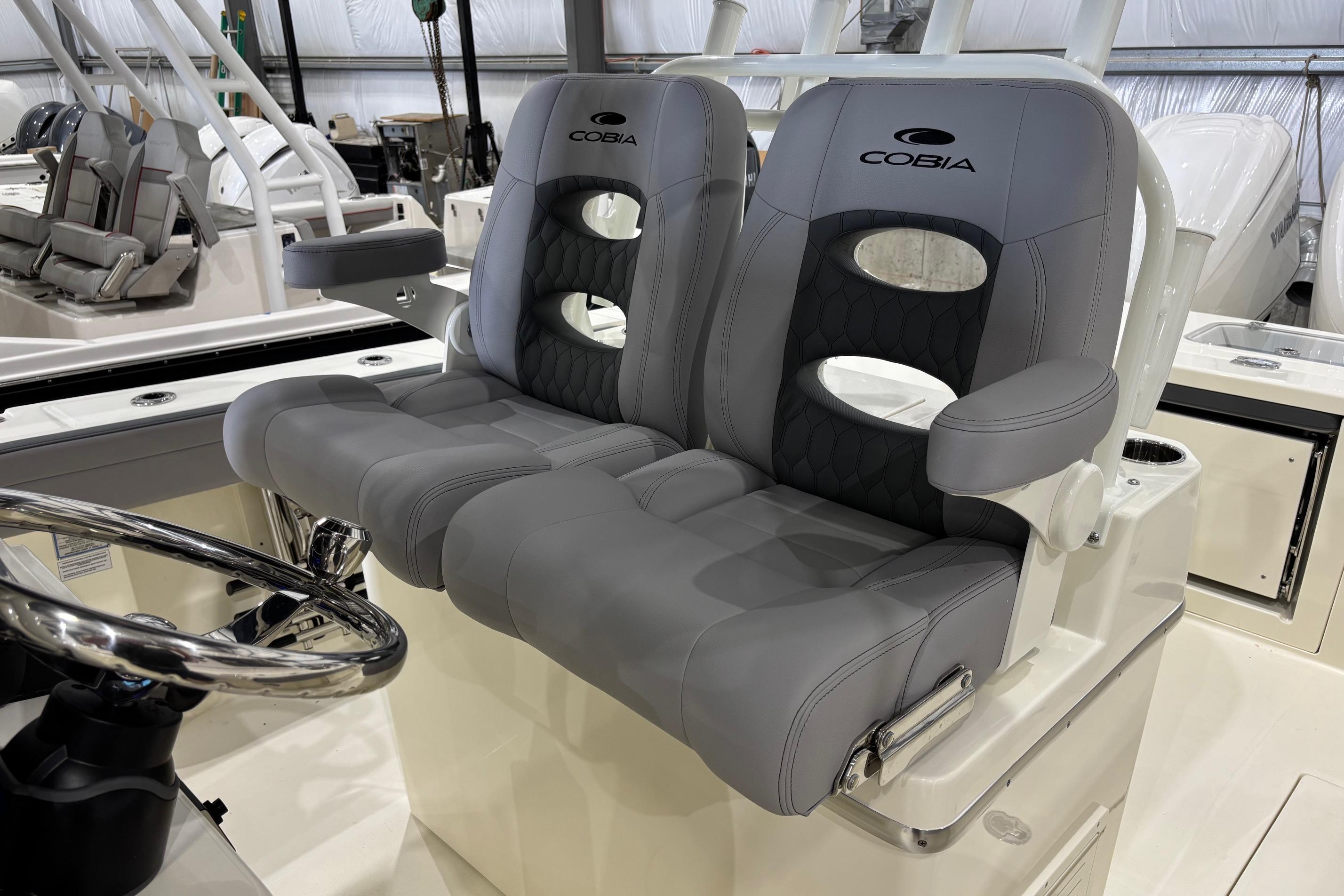 2026 Cobia 285 Open Center Console boat seats with armrests and steering wheel.