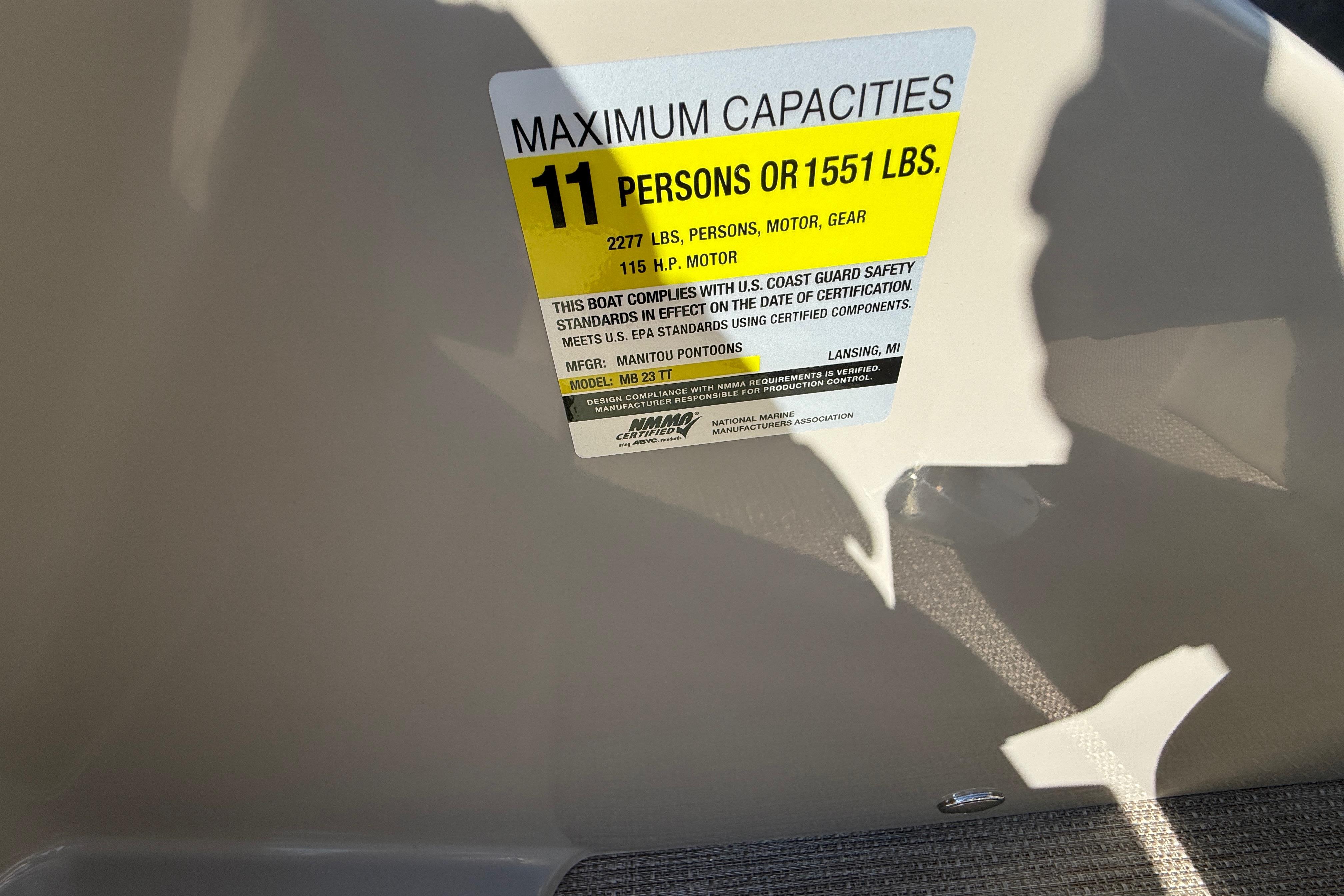 Sticker displaying maximum capacity for 2027 Manitou Aurora RF 23 boat: 11 persons or 1551 lbs.