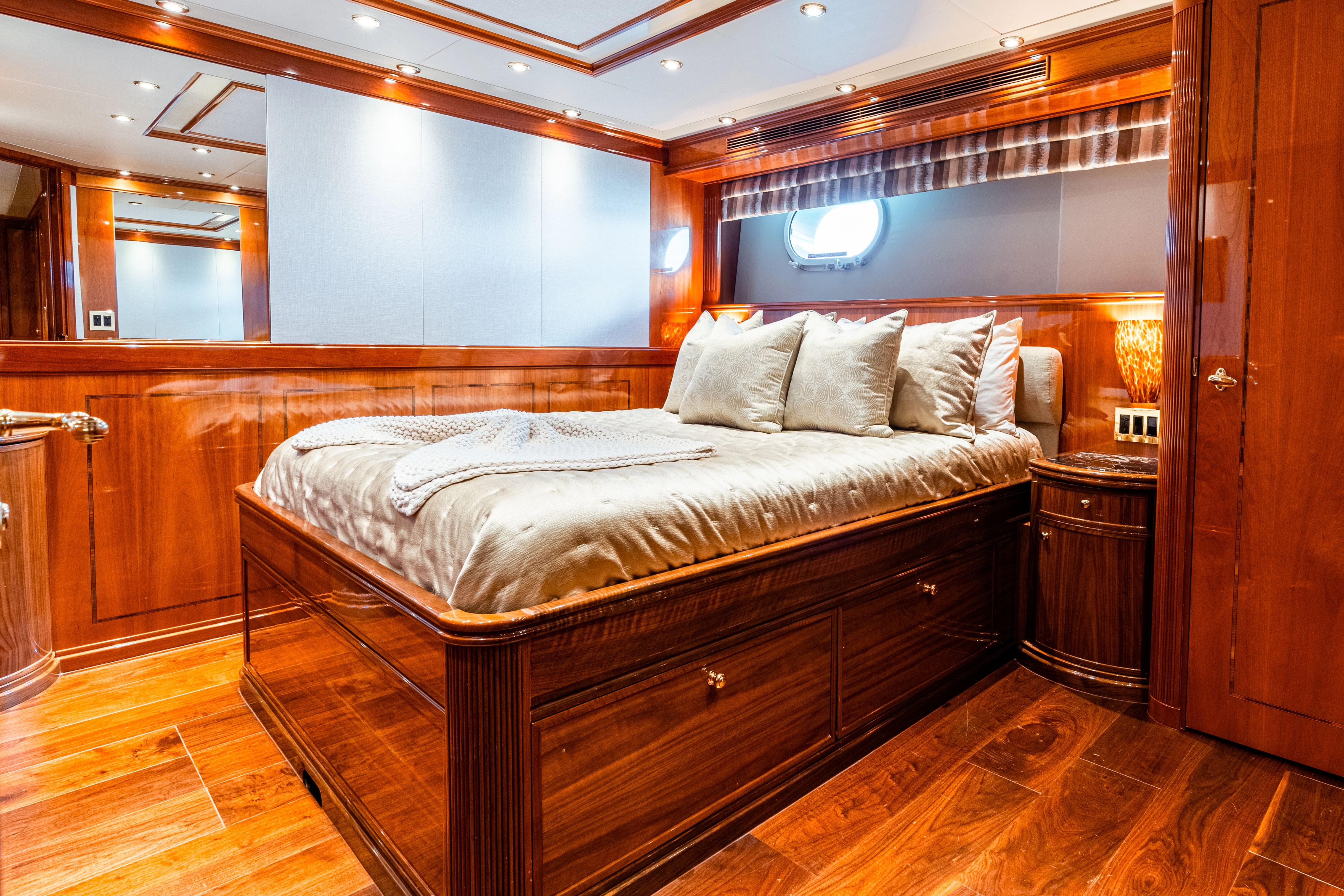Luxurious cabin with wooden floors and a large bed, surrounded by elegant wood paneling and soft lighting.