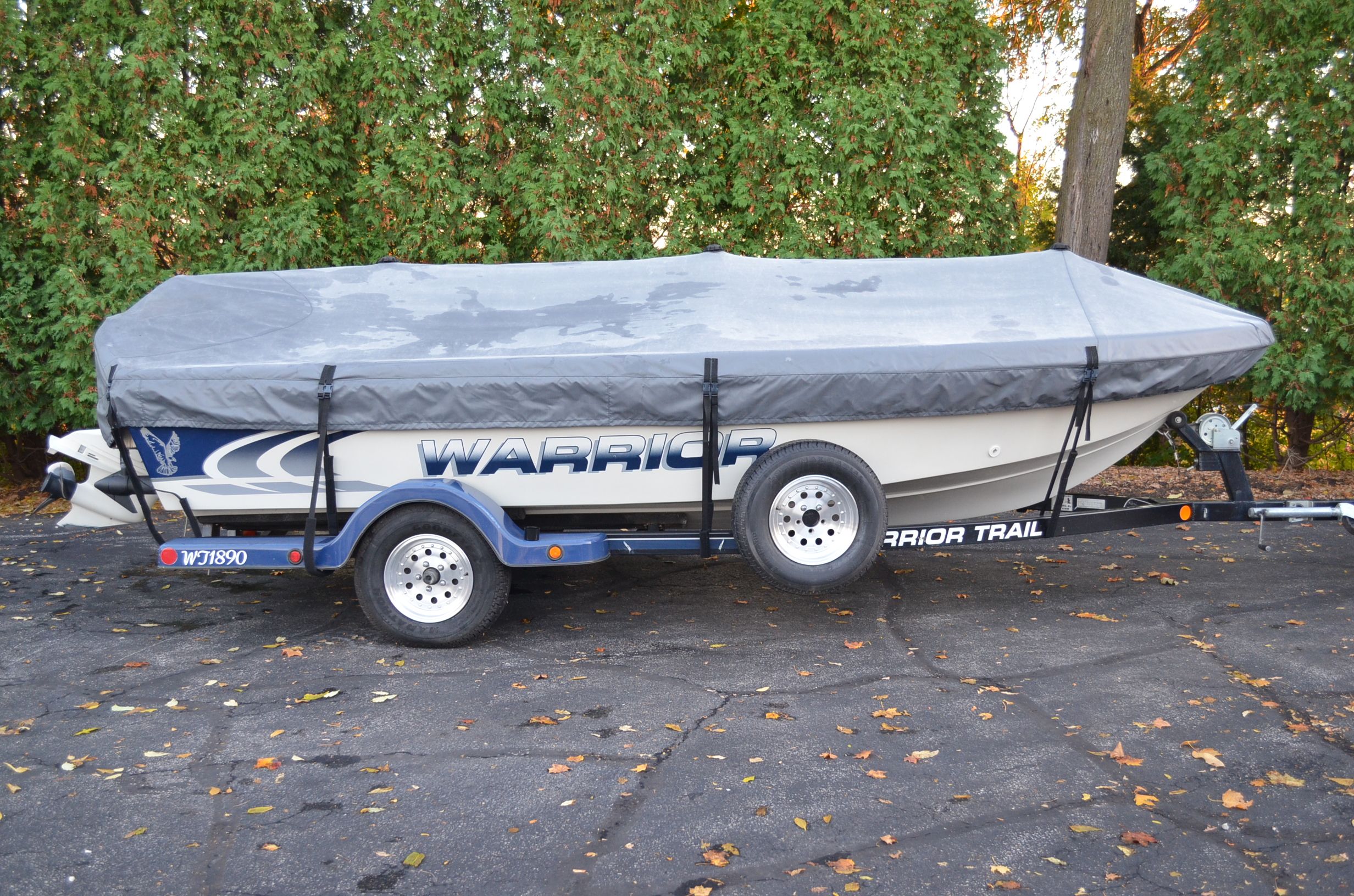 A 2000 Warrior V1890 Backtroller Eagle boat on a trailer, covered with a gray tarp.