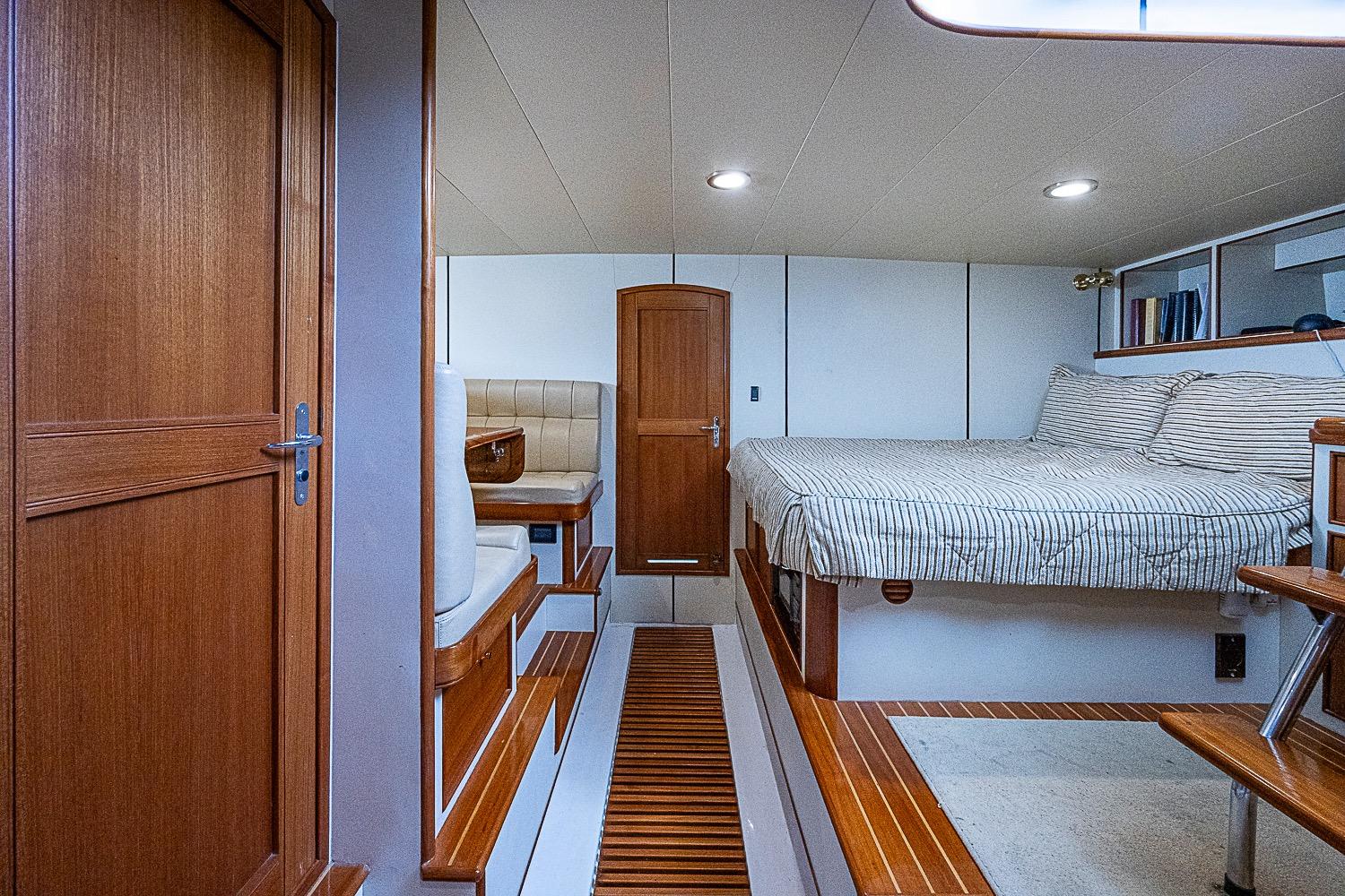 Luxurious cabin interior of 2014 Marlow 80 Explorer yacht with wood accents and cozy bedding.