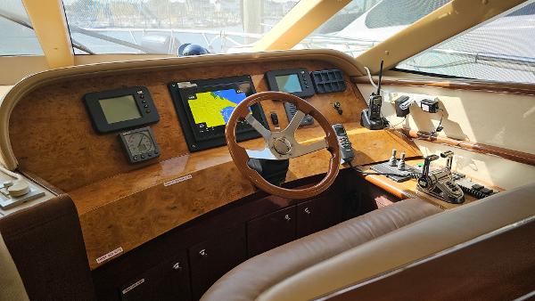 Helm of 2005 Neptunus 56 Flybridge yacht with navigation equipment and wooden steering wheel.