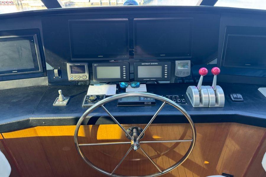 Control panel of a 2002 Viking 61 Enclosed Bridge yacht with steering wheel and navigation equipment.