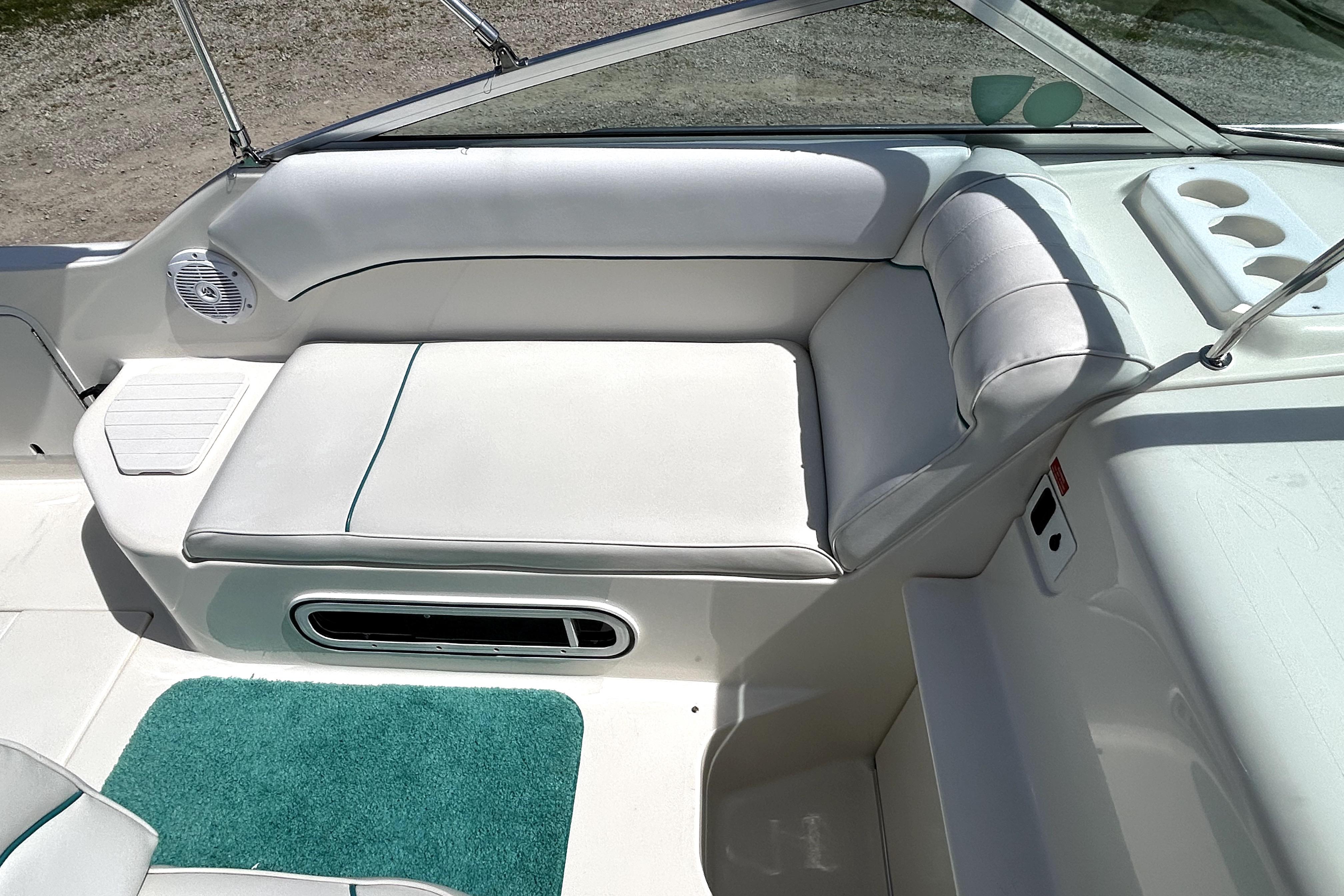 1995 Sea Ray 250 Sundancer boat interior with white seating and teal carpet.