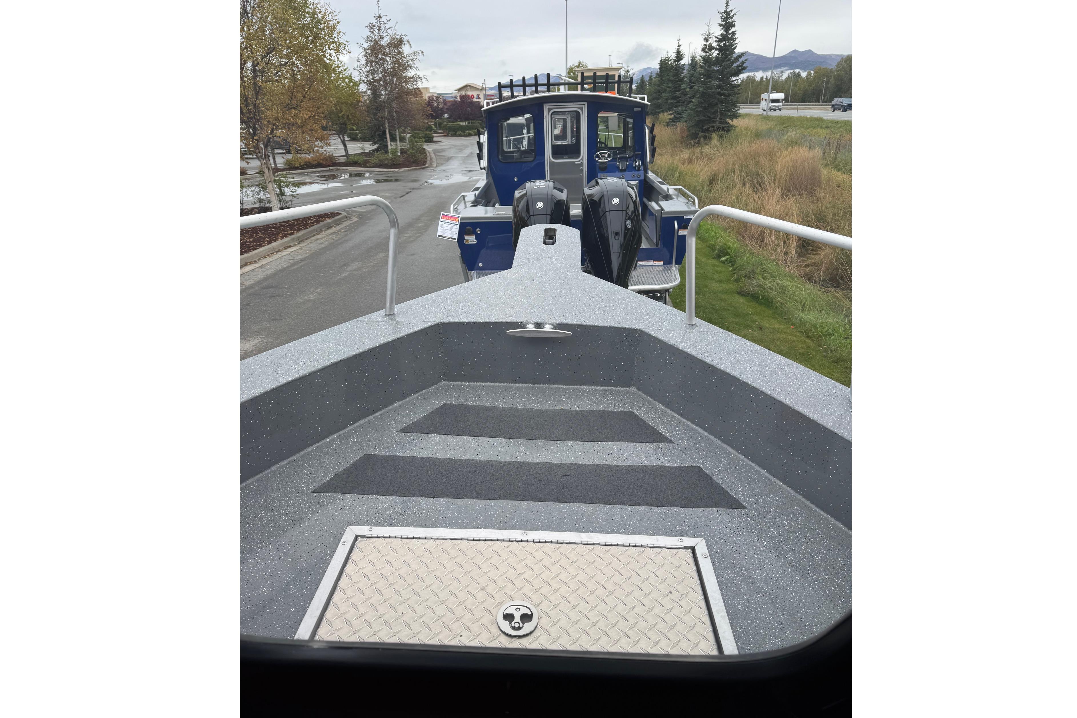 2024 Spartan 24 MAXIMUS PRO XL boat on trailer, parked on a road with trees.