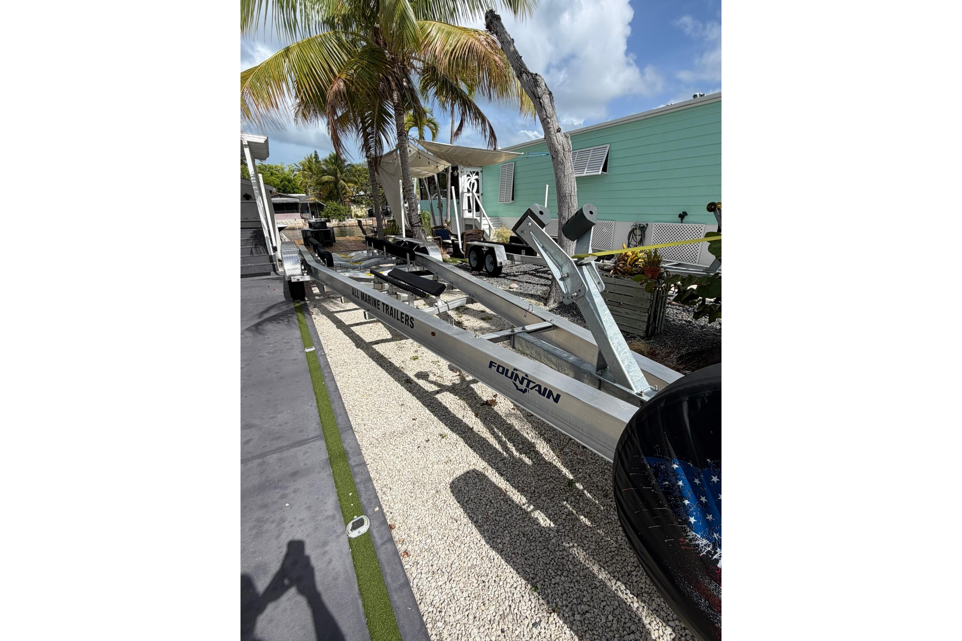 Trailer for 2007 Fountain 34 Center Console boat, parked outdoors near palm trees.