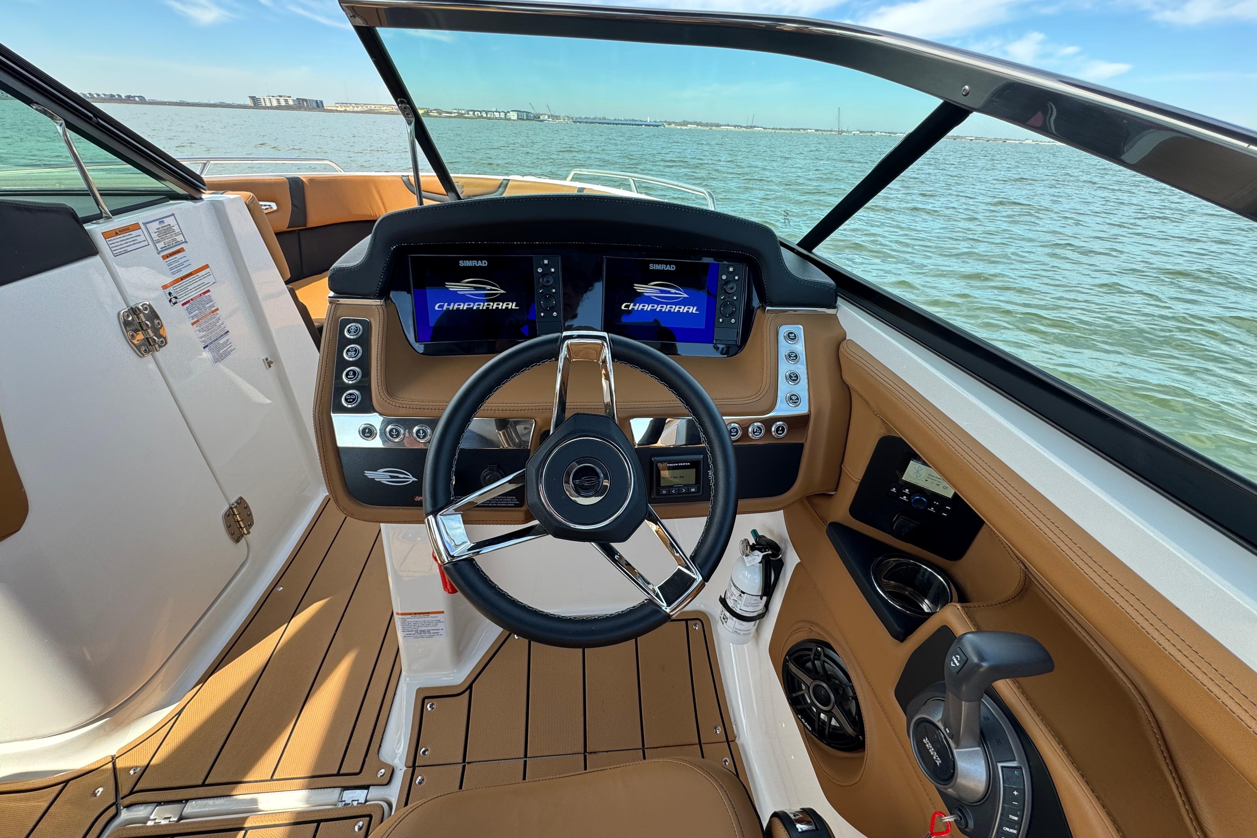 2023 Chaparral 26 Surf boat dashboard with modern controls and steering wheel on open water.