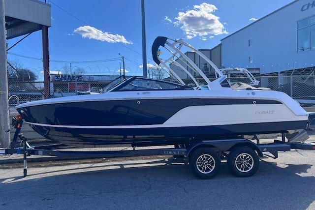 2025 Cobalt CS23 Surf boat on trailer, parked outdoors under a clear blue sky.