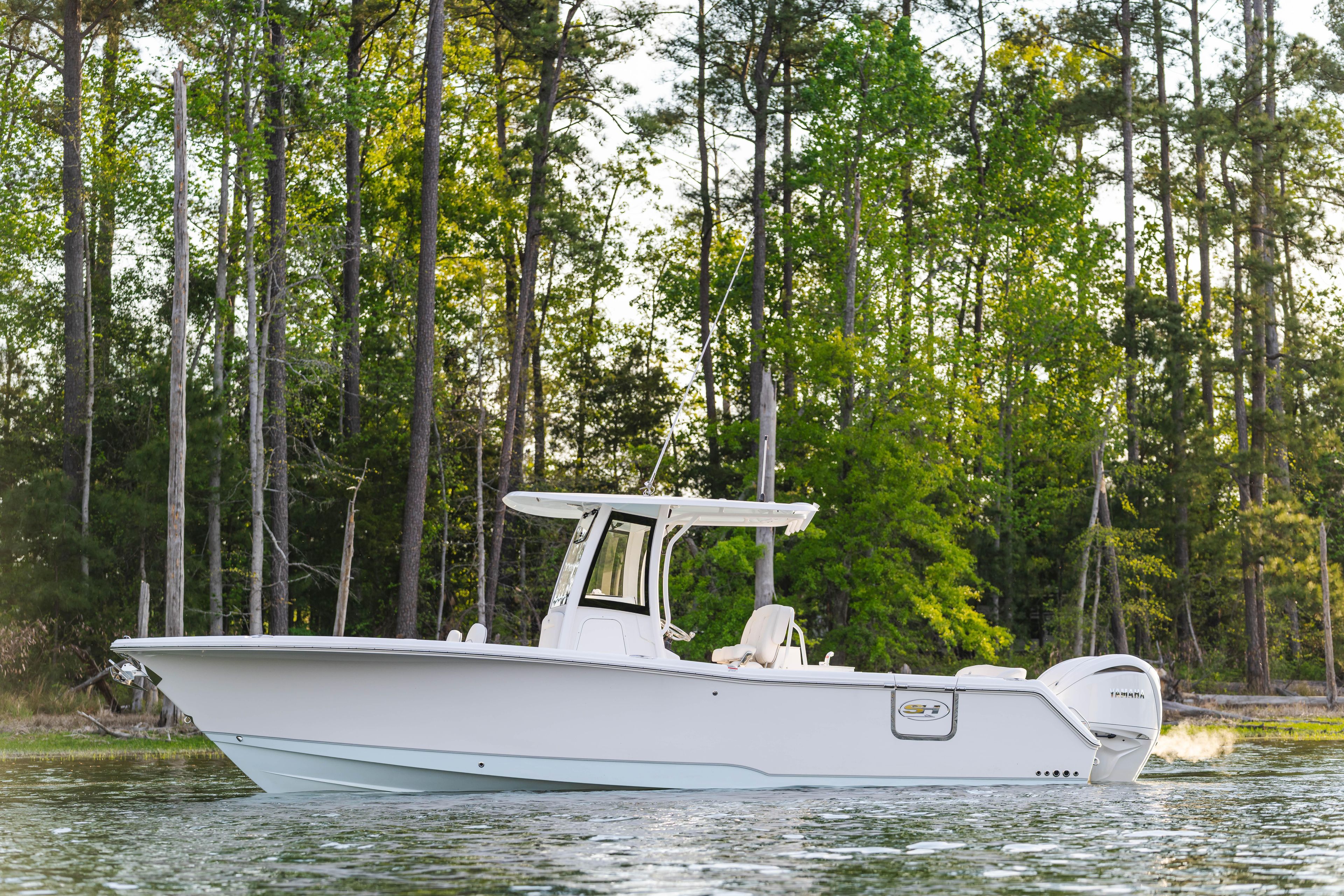 2027 Sea Hunt Ultra 275 SE boat on a serene lake with forest backdrop.