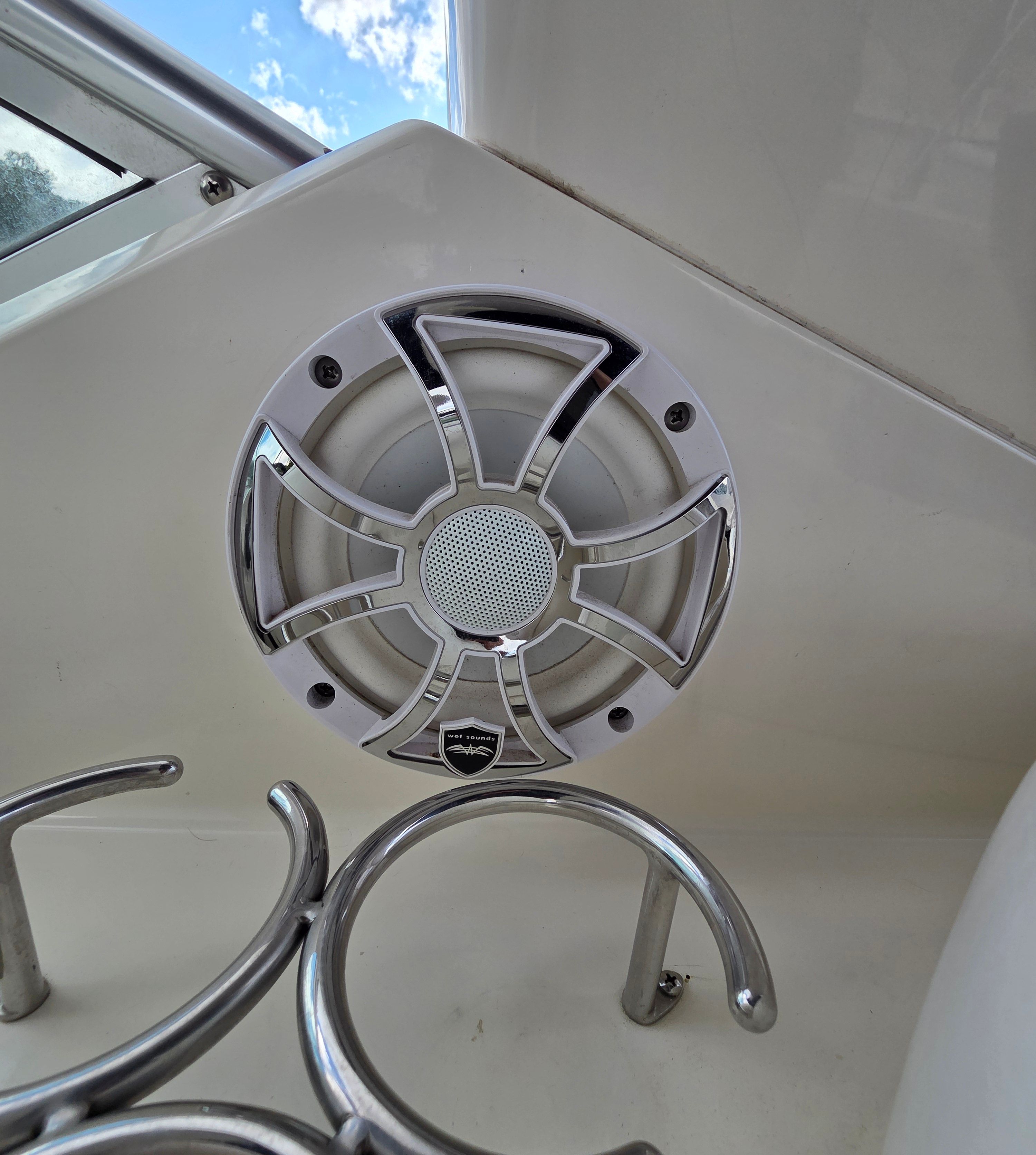 Close-up of a speaker on a boat, surrounded by stainless steel holders.