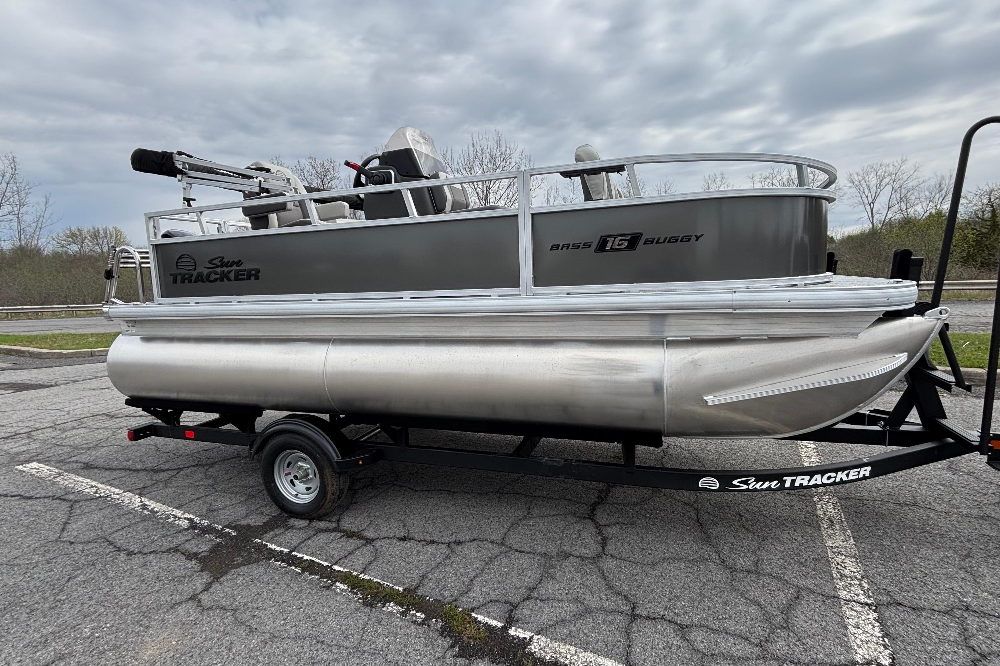 2026 Sun Tracker Bass Buggy 16 XL Select pontoon boat on trailer in parking lot.