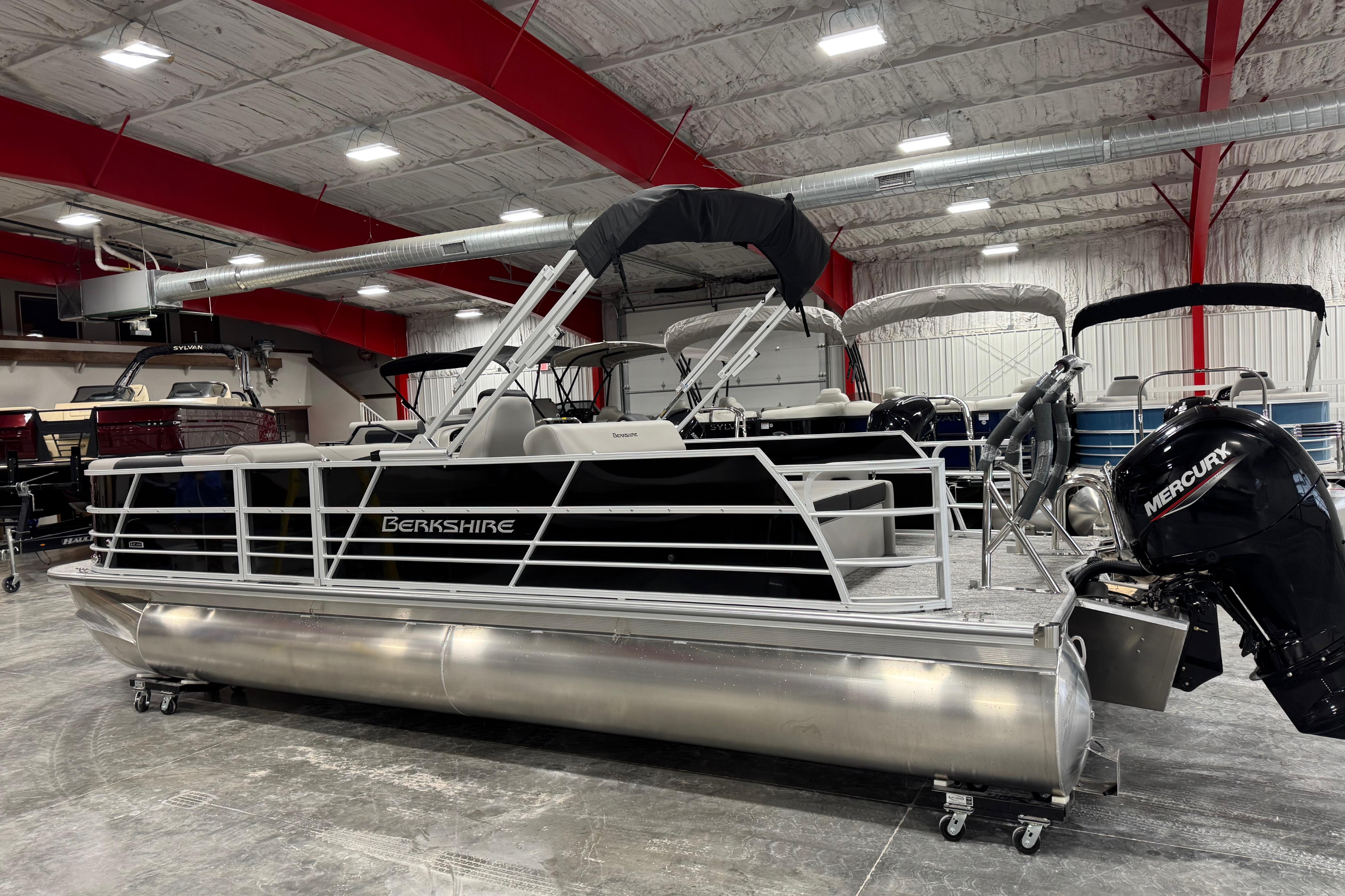 2026 Berkshire 24 UL LE pontoon boat in showroom with Mercury outboard motor.