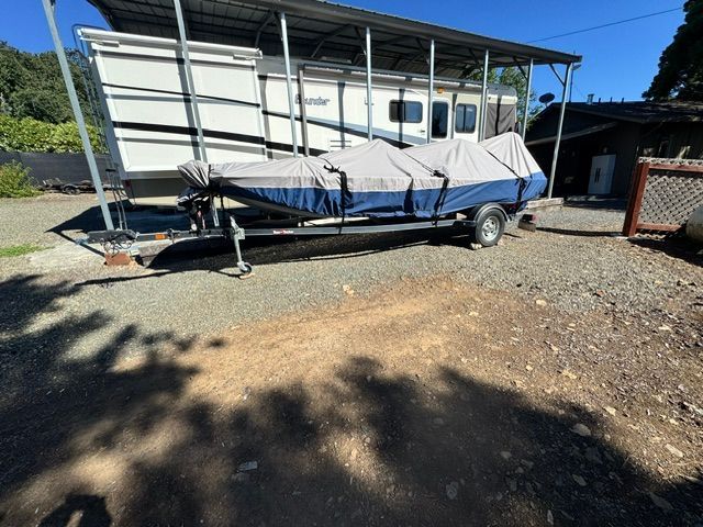 A 2020 Bass Tracker Tracker Pro Classic on a trailer, covered and parked next to an RV.