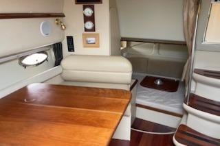 Interior of 2002 Cruisers Yachts 3372 Express, featuring wood table and cozy seating area.