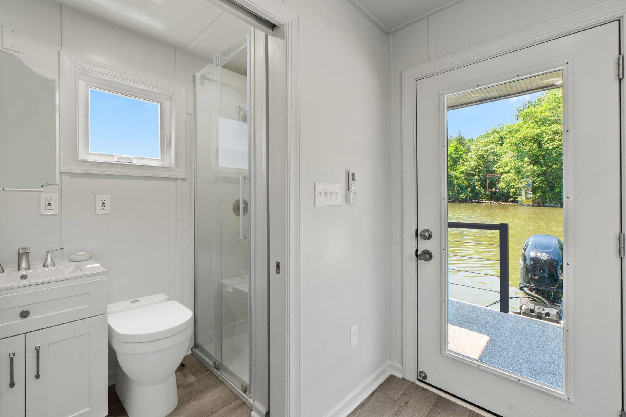 Modern bathroom on Hank's 40 Houseboat, 2025, with river view through glass door.