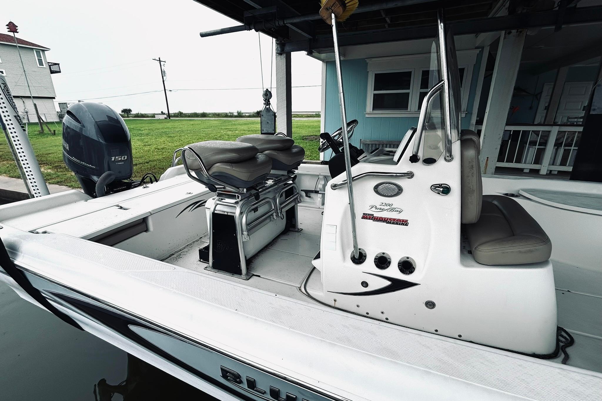 2017 Blue Wave 2200 PureBay boat with Yamaha 150 engine, docked near a house.