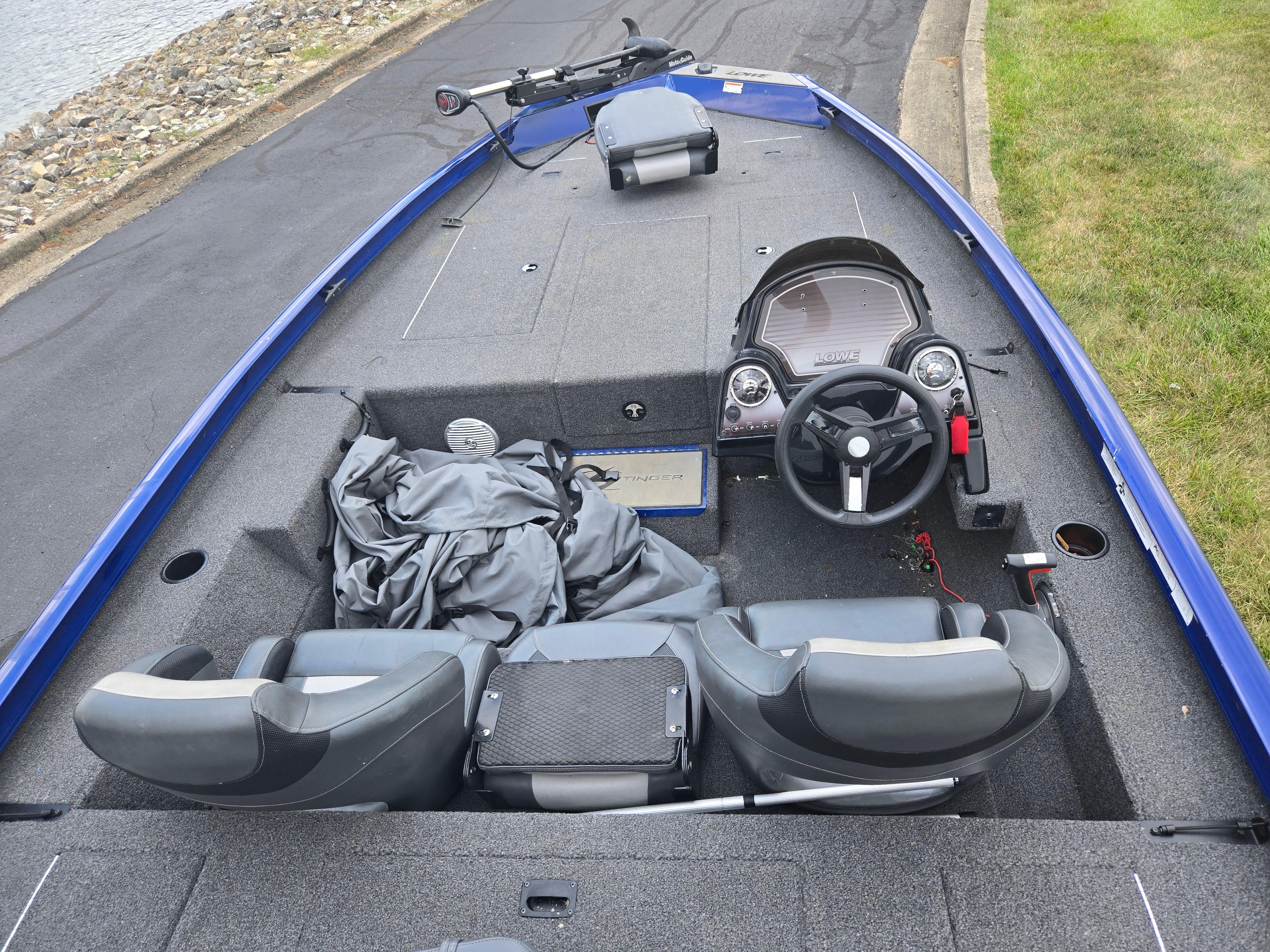 2021 Lowe Stinger 188 boat interior with steering wheel and seating, docked by a lakeside.