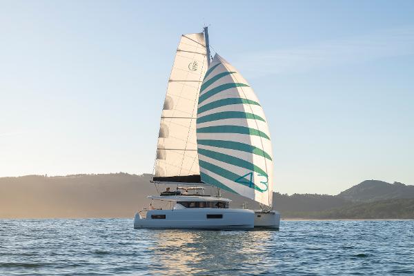 2025 Lagoon 43 catamaran sailing on calm waters at sunset.