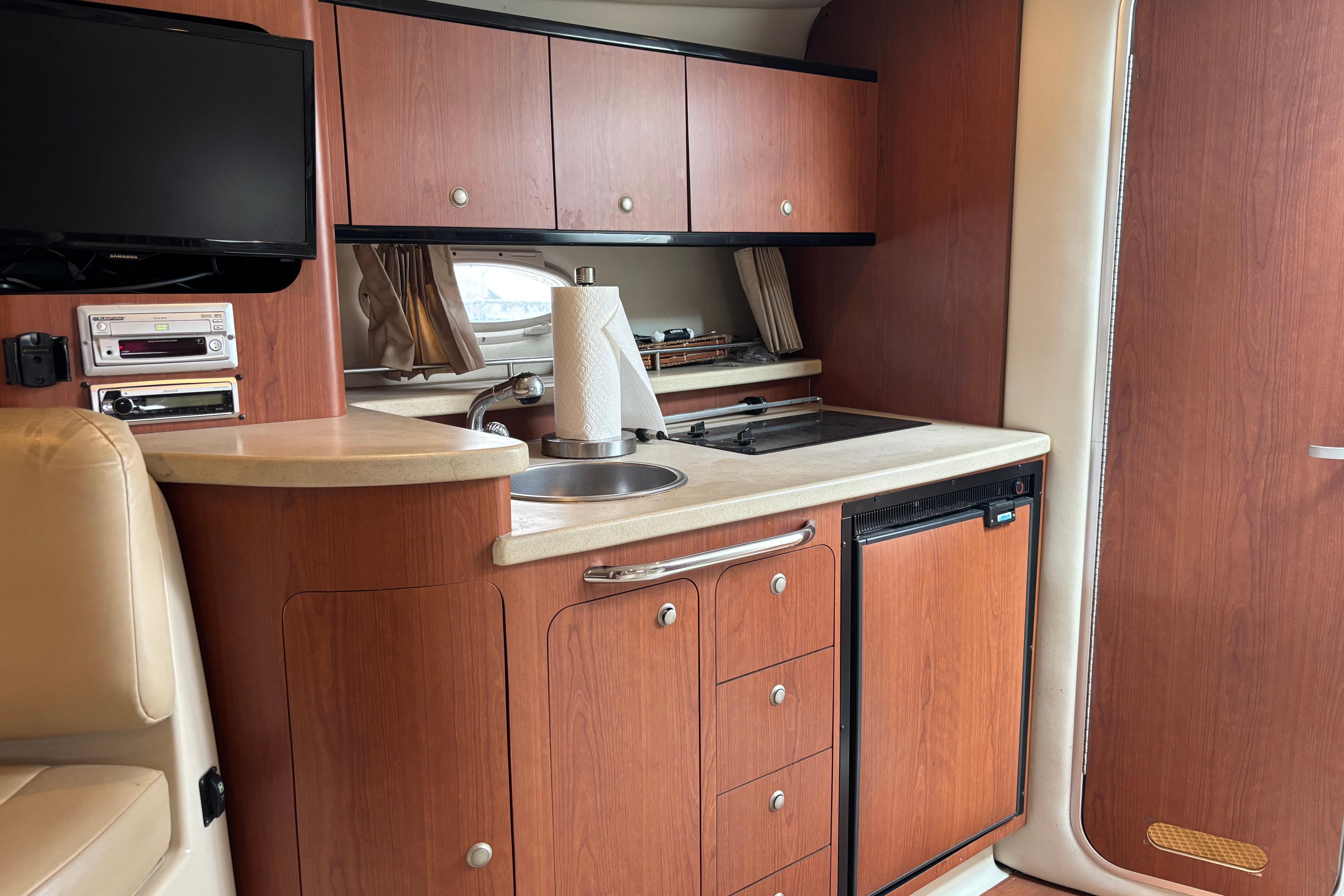 2004 Chaparral Signature 330 yacht interior with kitchenette, TV, and wooden cabinetry.