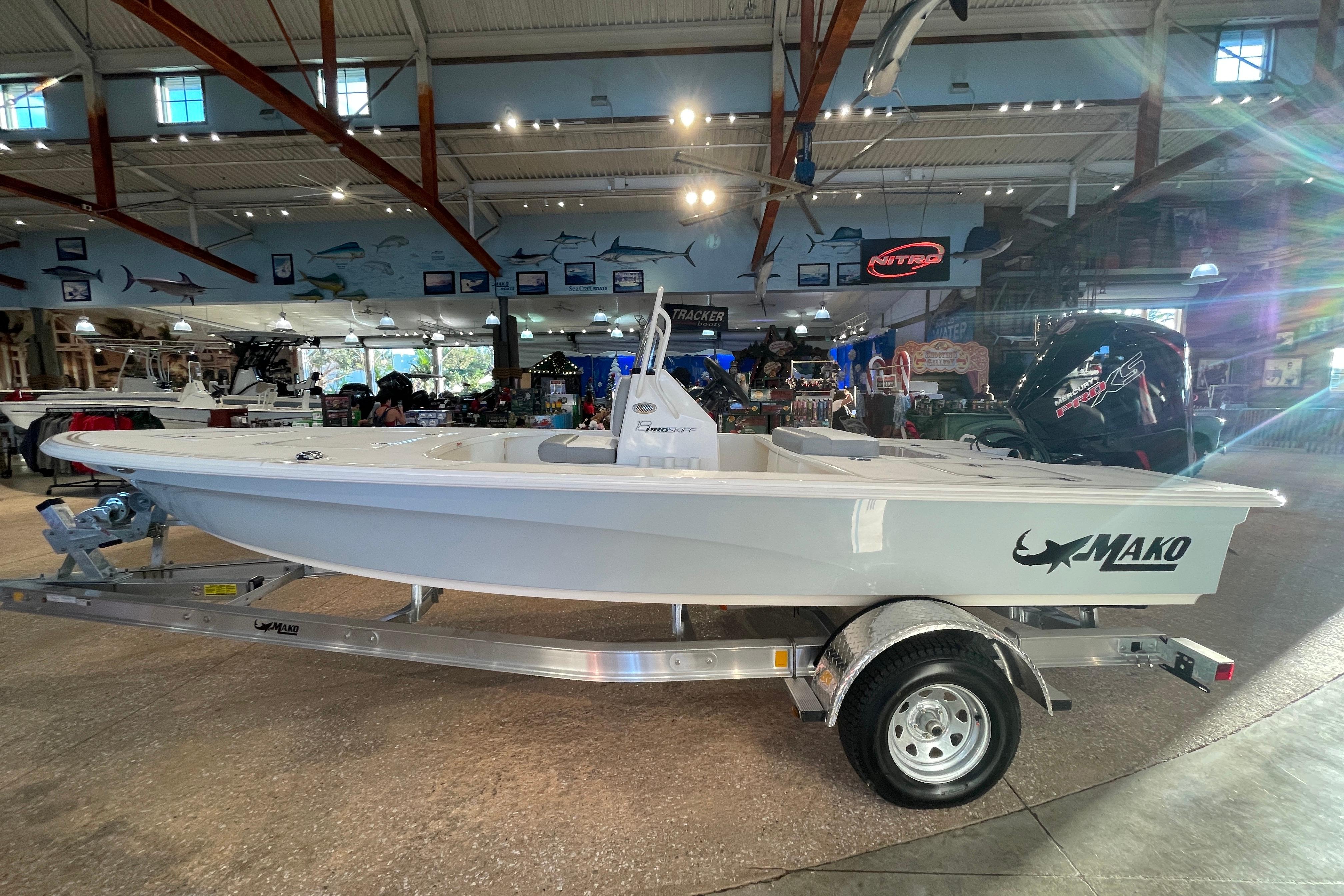 2026 Mako 18 Pro Skiff boat displayed in a showroom, on a trailer.