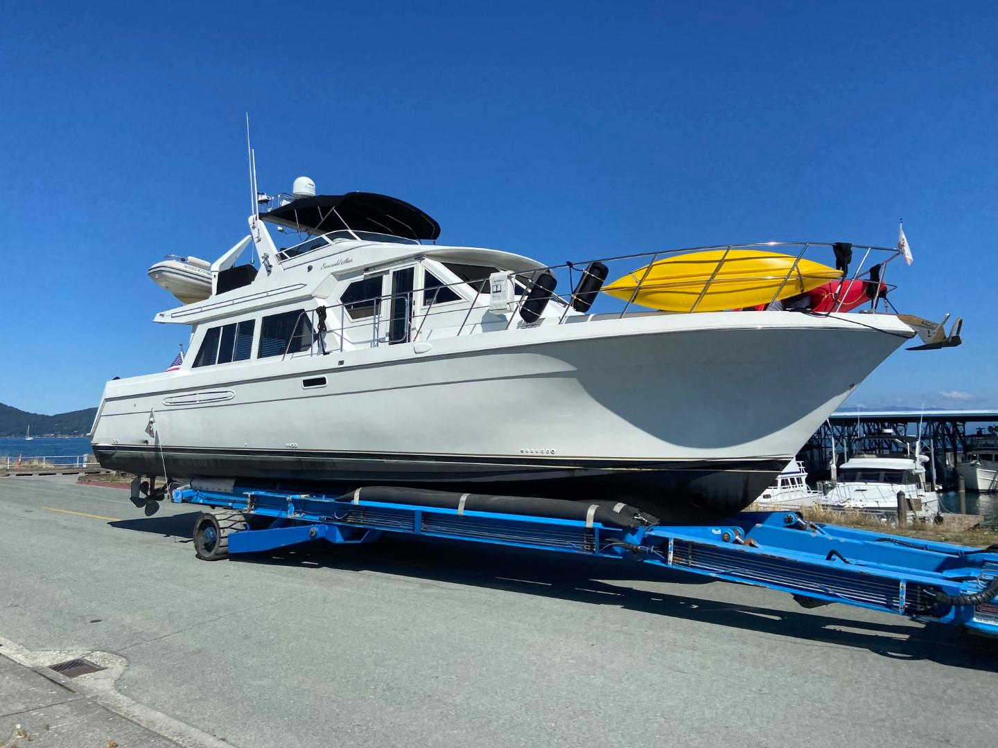 2002 Navigator 5700 Rival yacht on trailer with kayaks, under clear blue sky.
