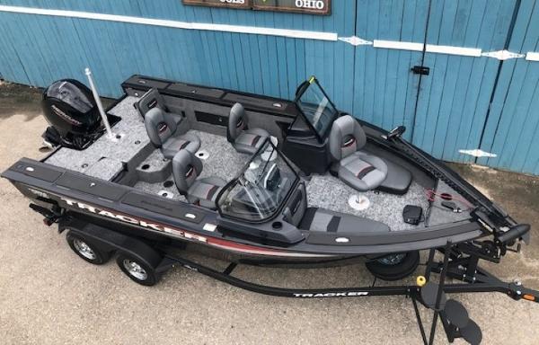 2025 Tracker Targa V18 Combo boat with trailer, parked near a blue wooden wall.