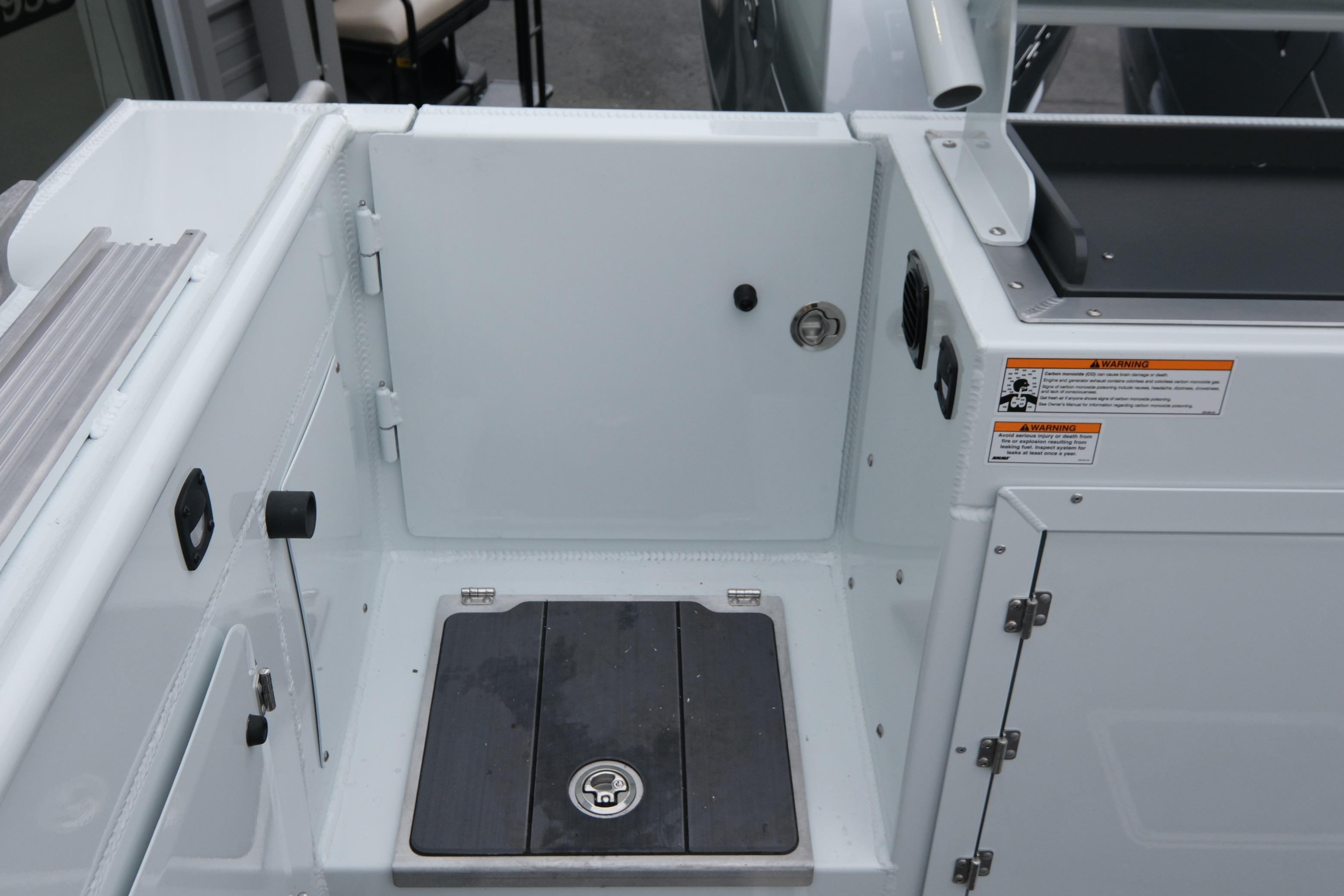 2026 Hewescraft 270 Pacific Explorer boat deck with storage compartment and safety warnings.