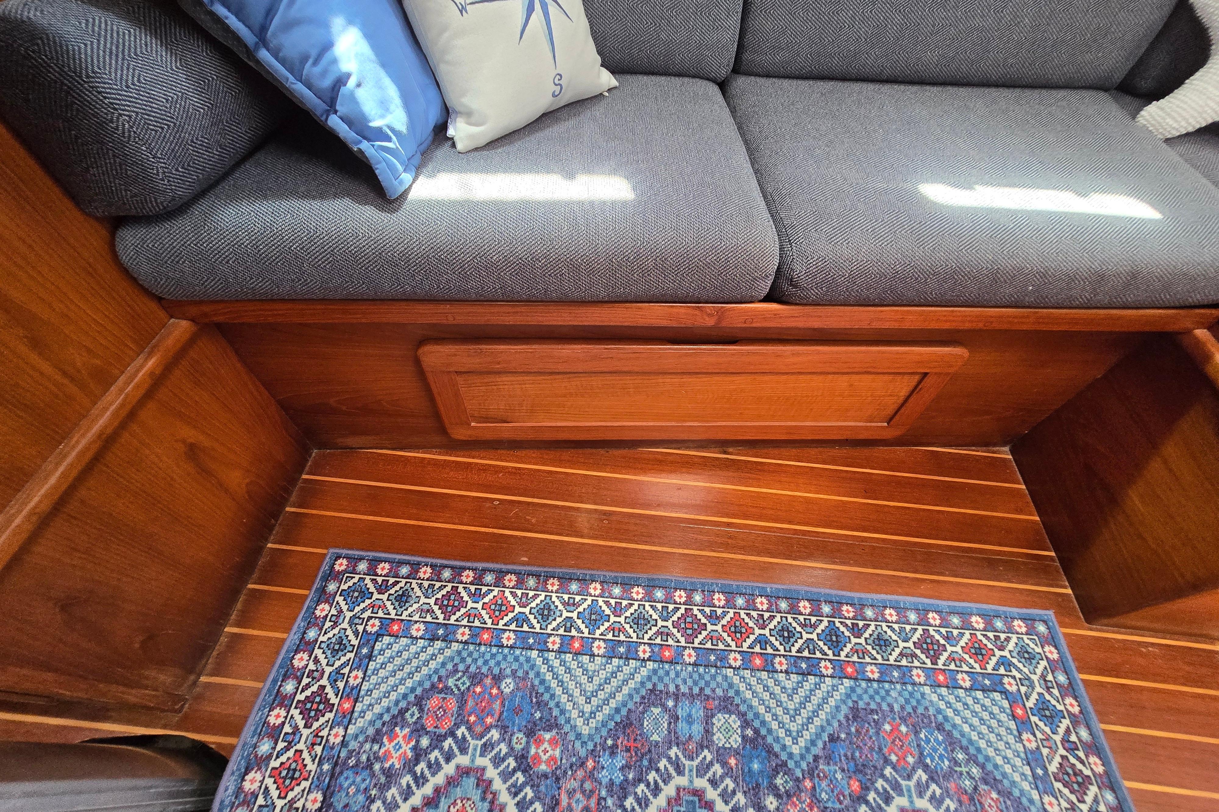 Cozy interior of a 1993 Caliber 35 sailboat with wooden flooring and patterned rug.