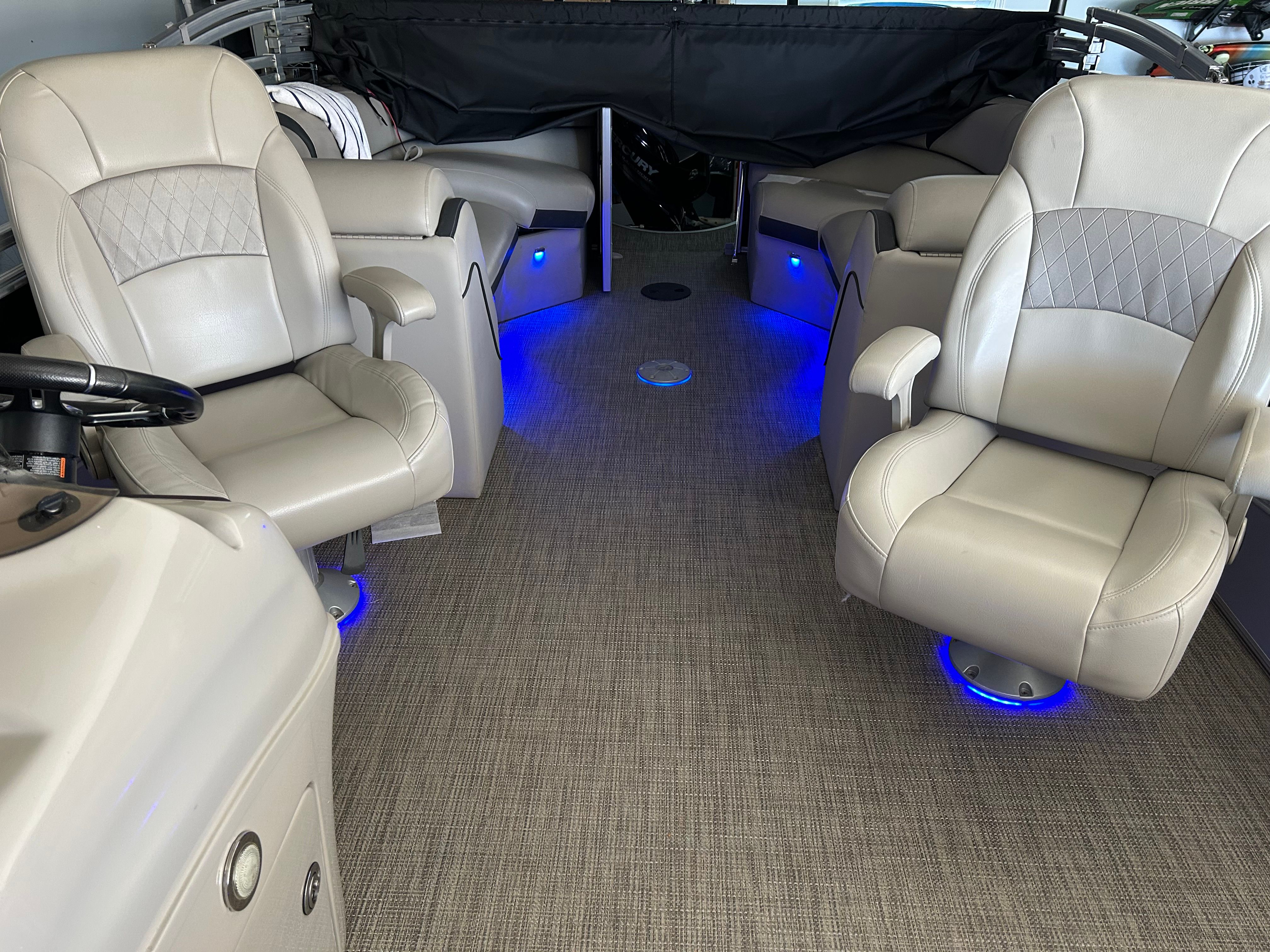 Interior of a boat with beige leather seats and blue lighting.