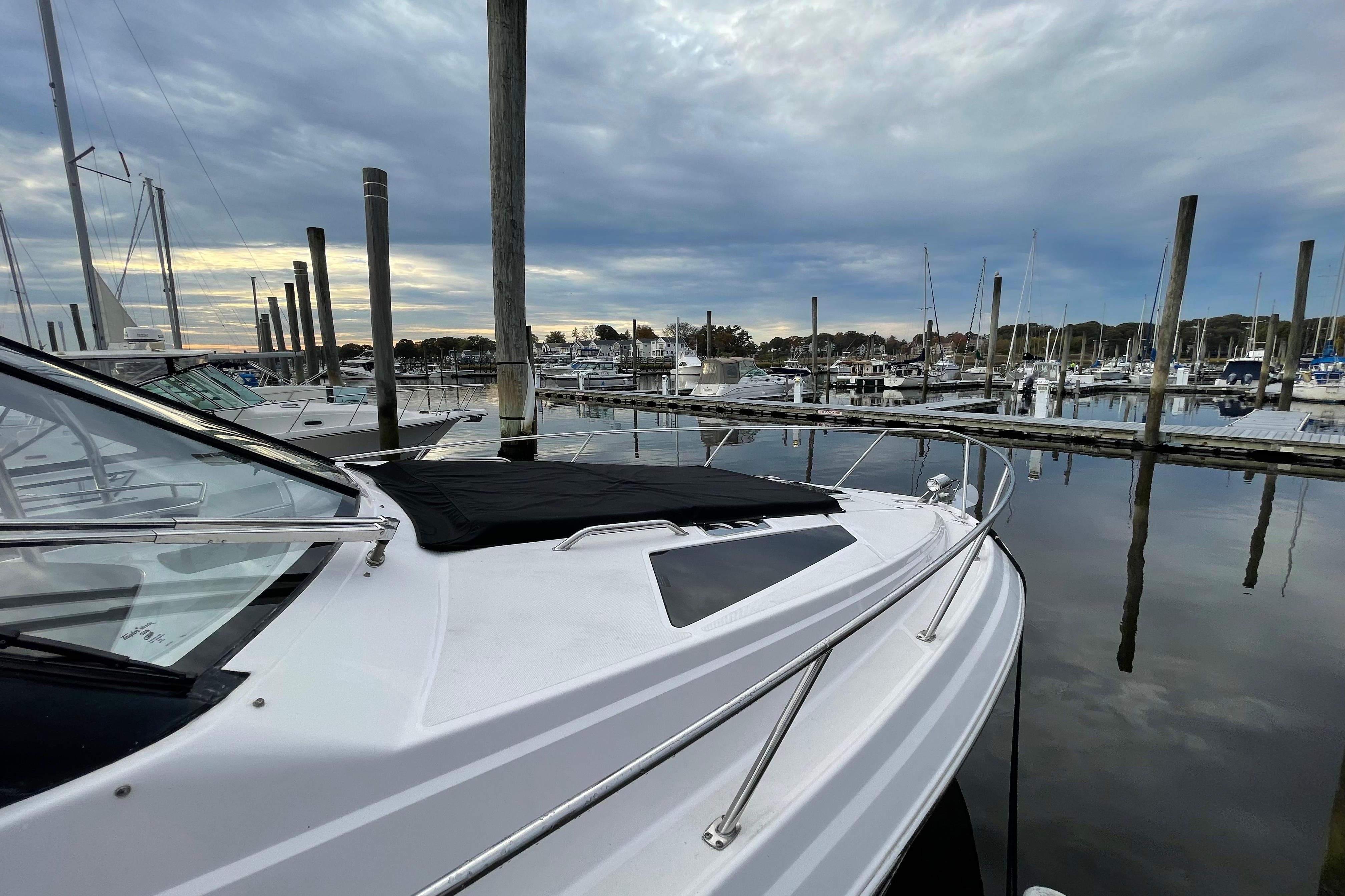 2012 Regal 35 Sport Coupe docked in a serene marina under cloudy skies.