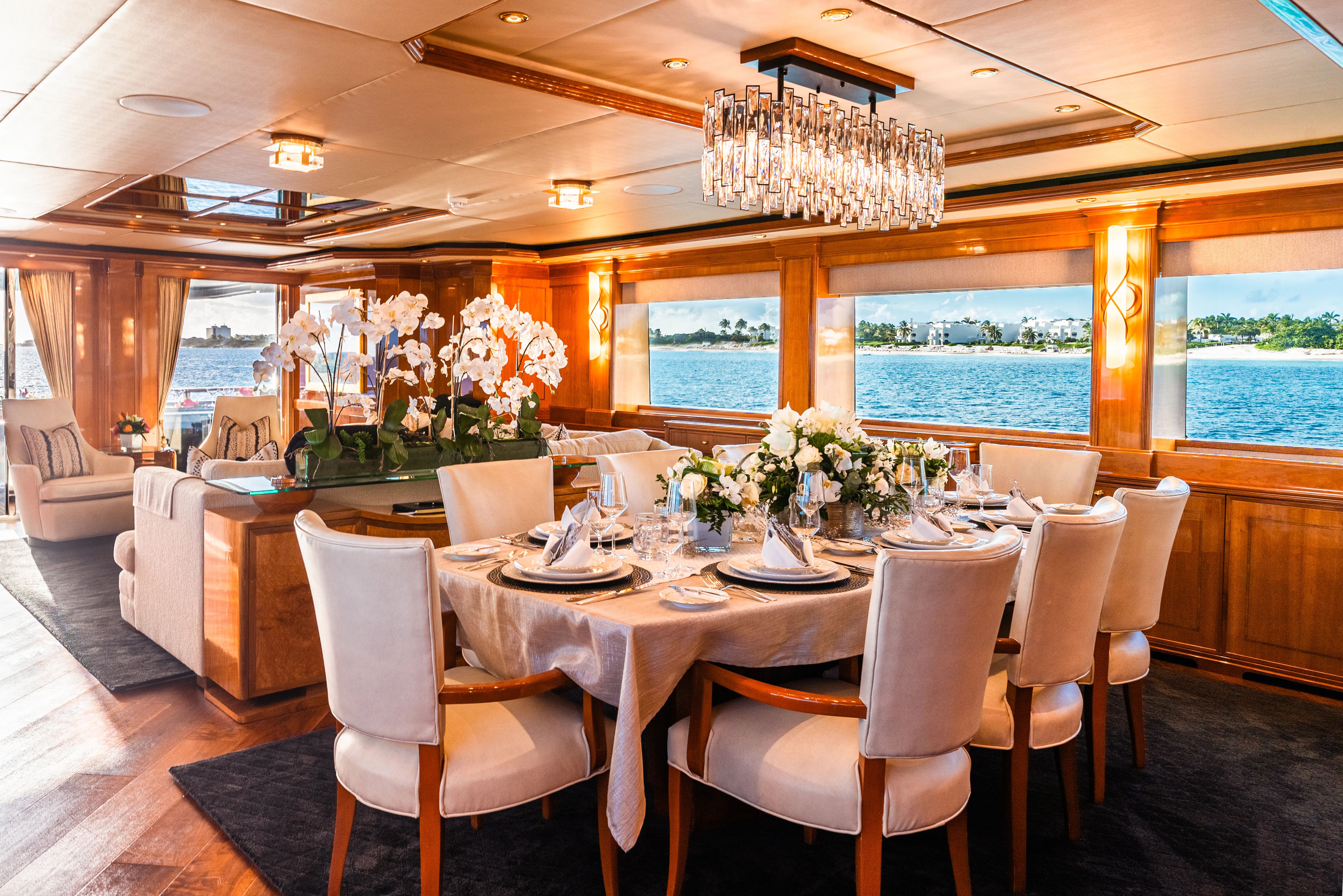 Elegant dining area on a luxury yacht with a set table and ocean view.