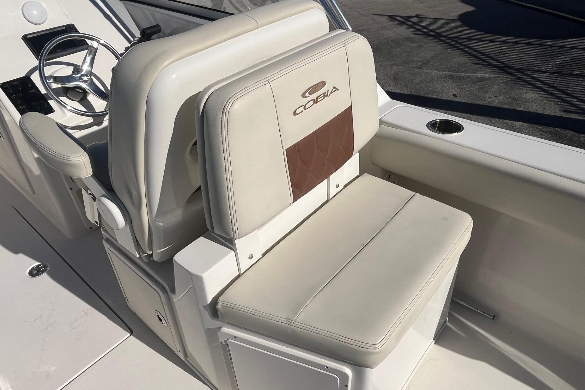 2023 Cobia 220 Dual Console boat interior with steering wheel and cushioned seating.