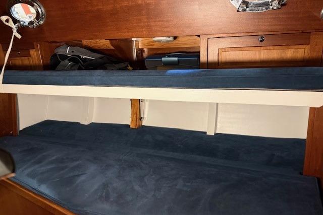 Interior cabin of 2010 Spirit Yachts R46 with blue bedding and wooden storage.