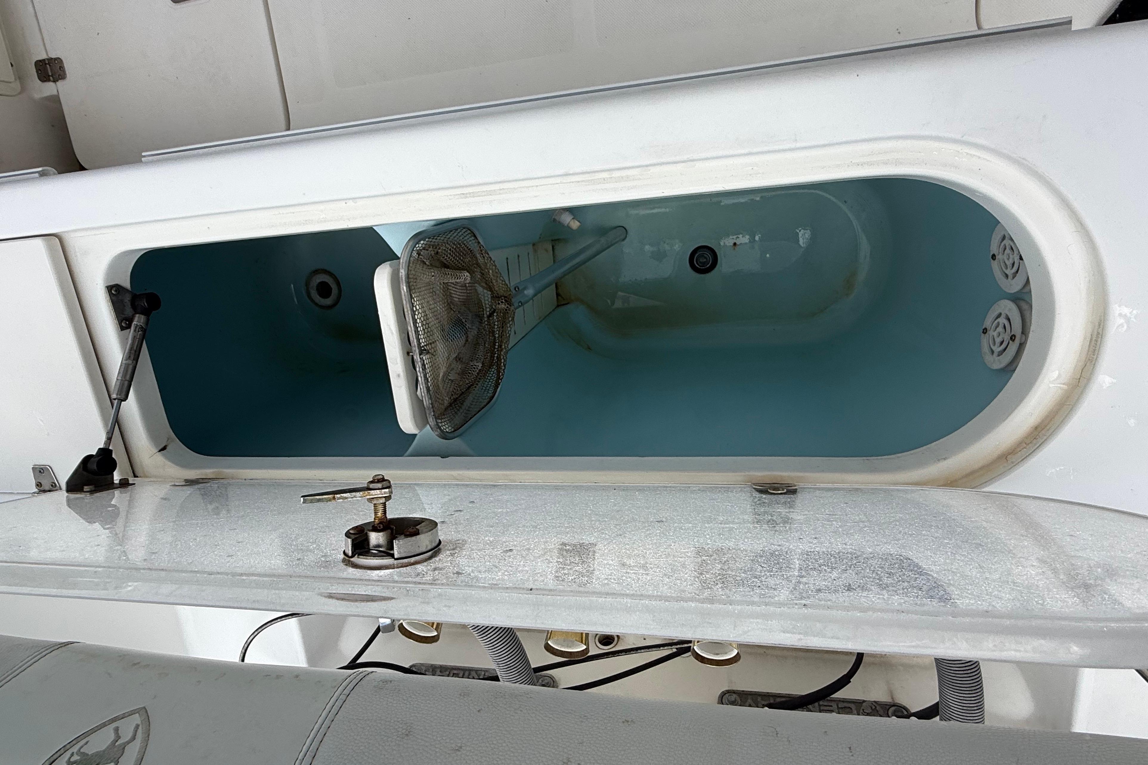 Open livewell on 2008 Century 2901 Center Console boat, featuring a net and water.