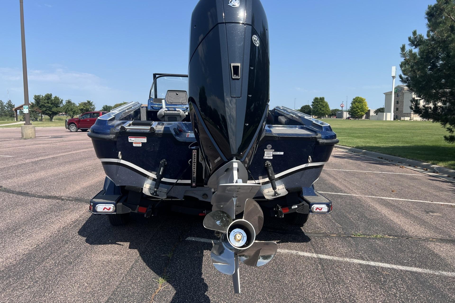 Rear view of a 2026 Nitro ZV21 Pro boat with an outboard motor in a parking lot.