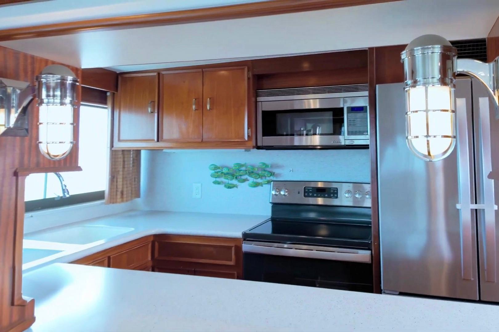 Kitchen interior of 1980 Hatteras 70 Motor Yacht with modern appliances and wooden cabinetry.