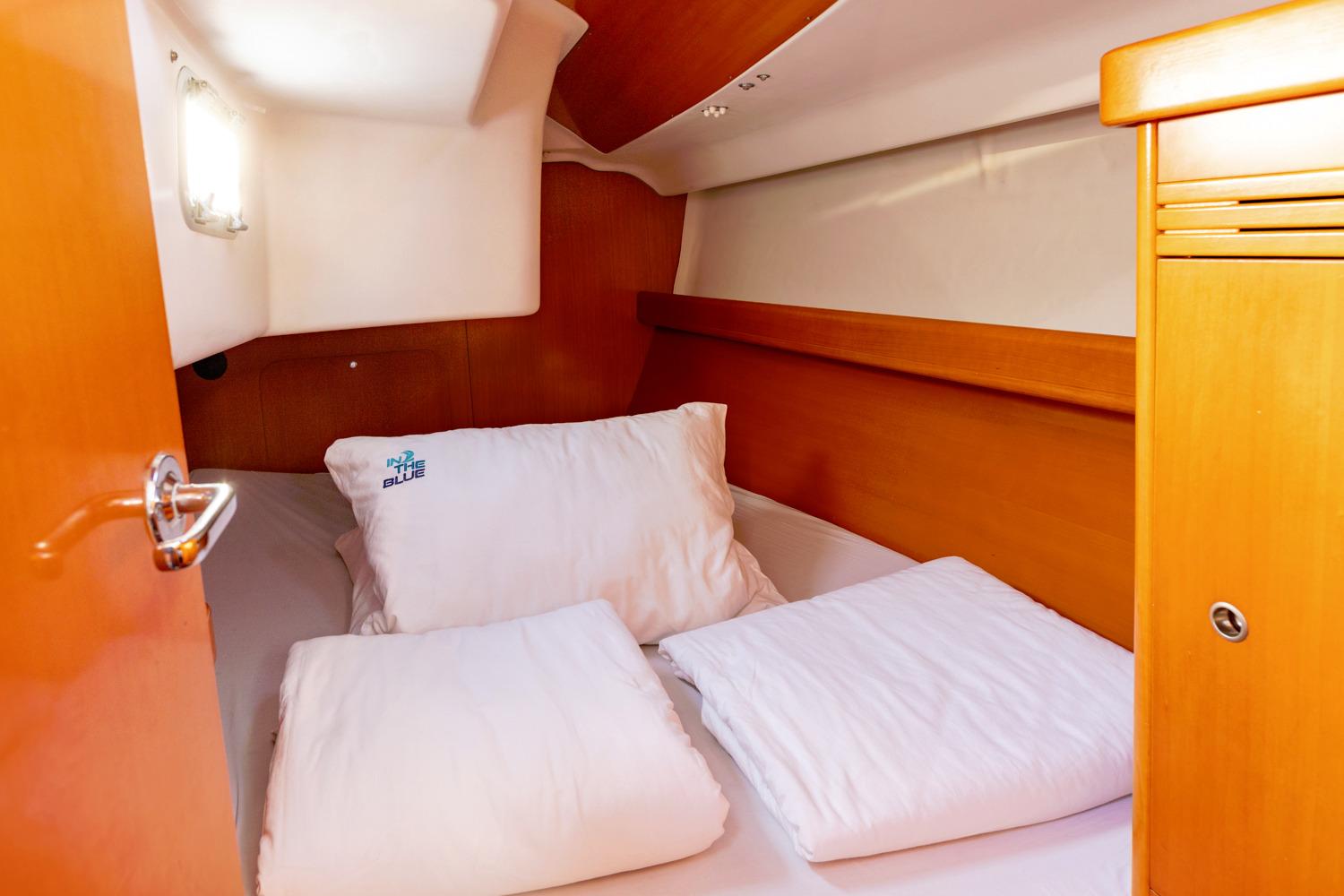 Cozy cabin interior of 2005 Beneteau First 40.7 sailboat with wooden finish and bedding.