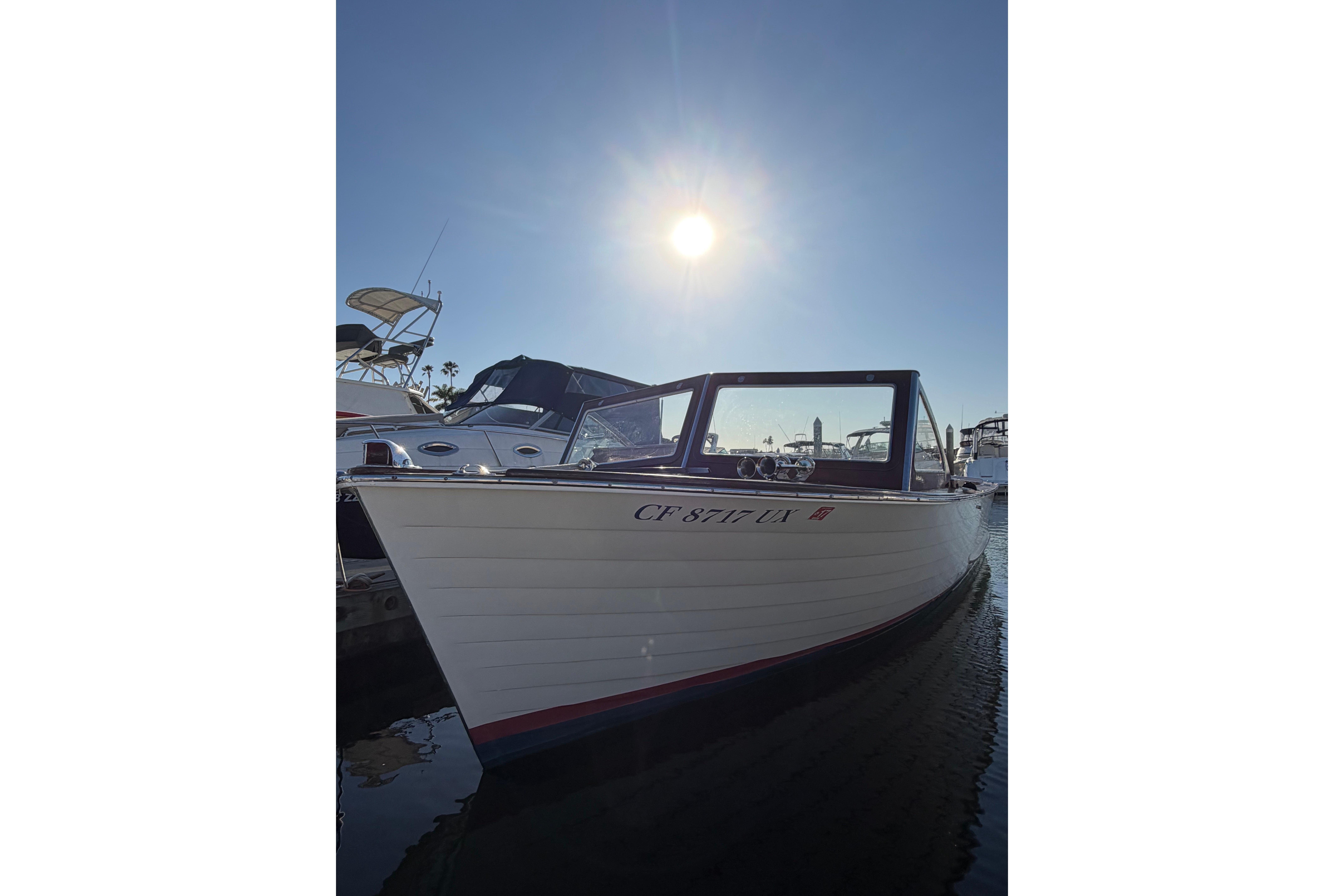 1964 Lyman 25 Sleeper boat docked under a bright sunlit sky.