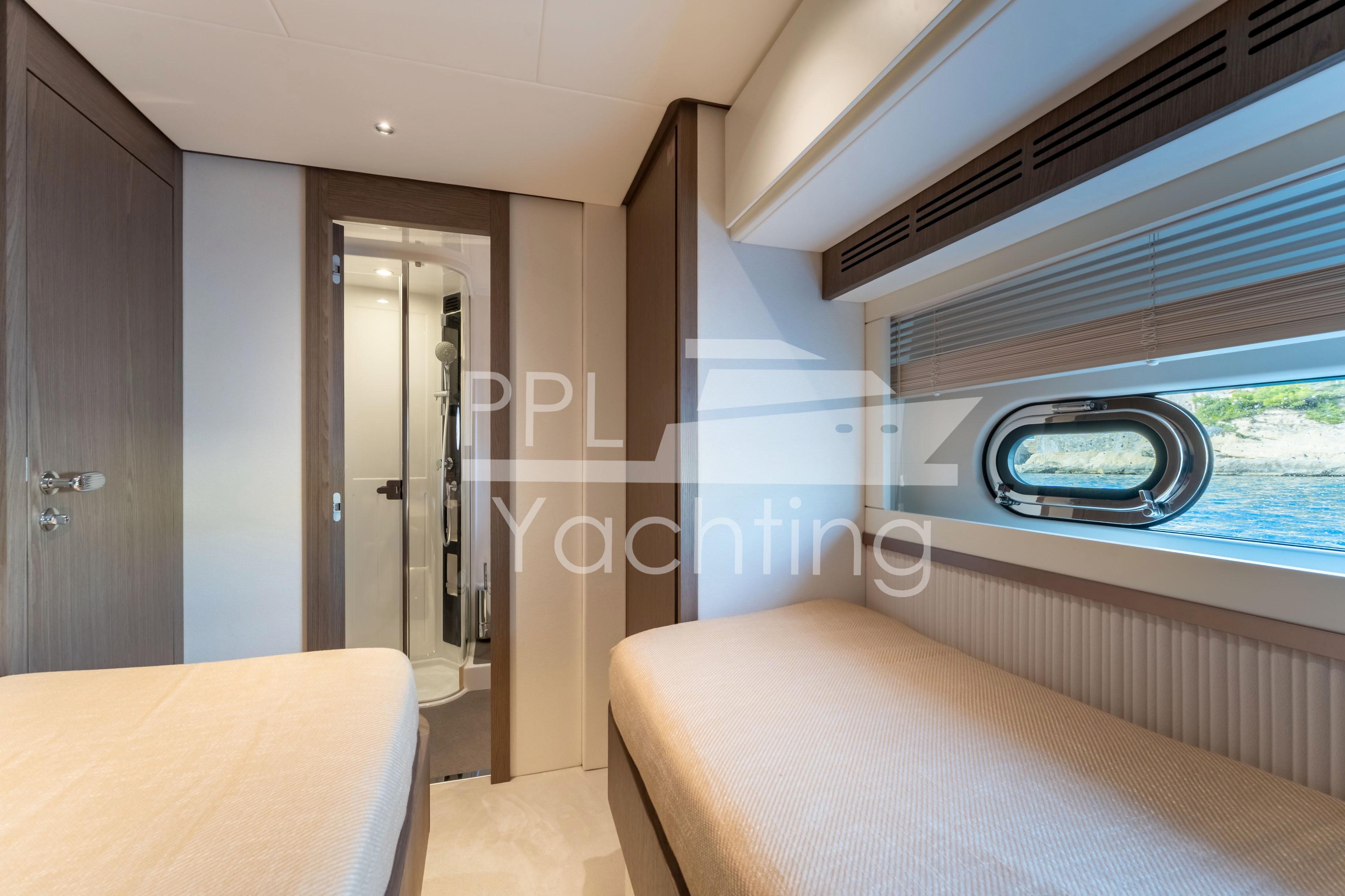 Interior of 2021 Azimut Magellano 66 yacht cabin with twin beds and ocean view.