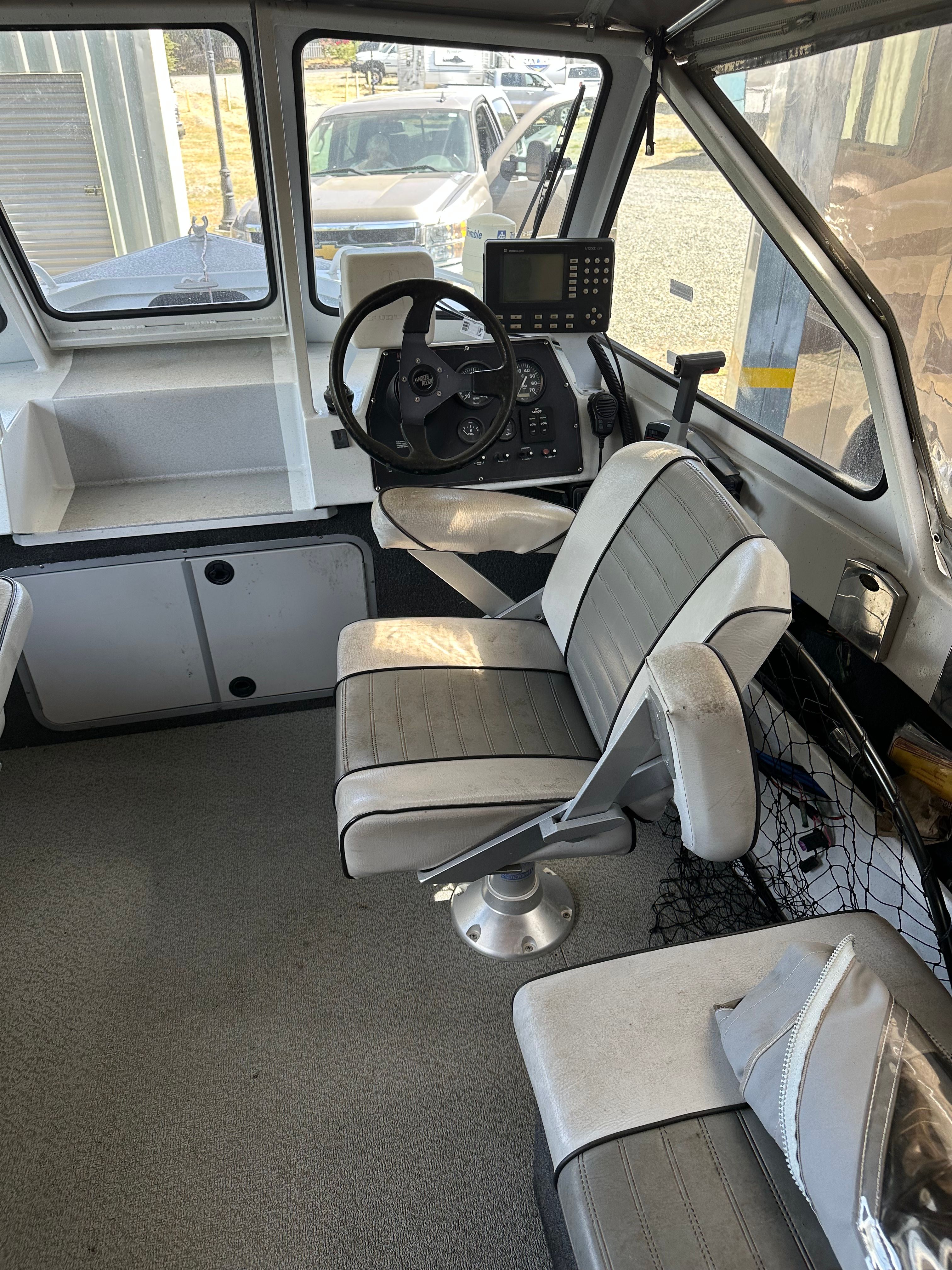 Interior of a 2006 aluminum boat with gray seats and a helm station.