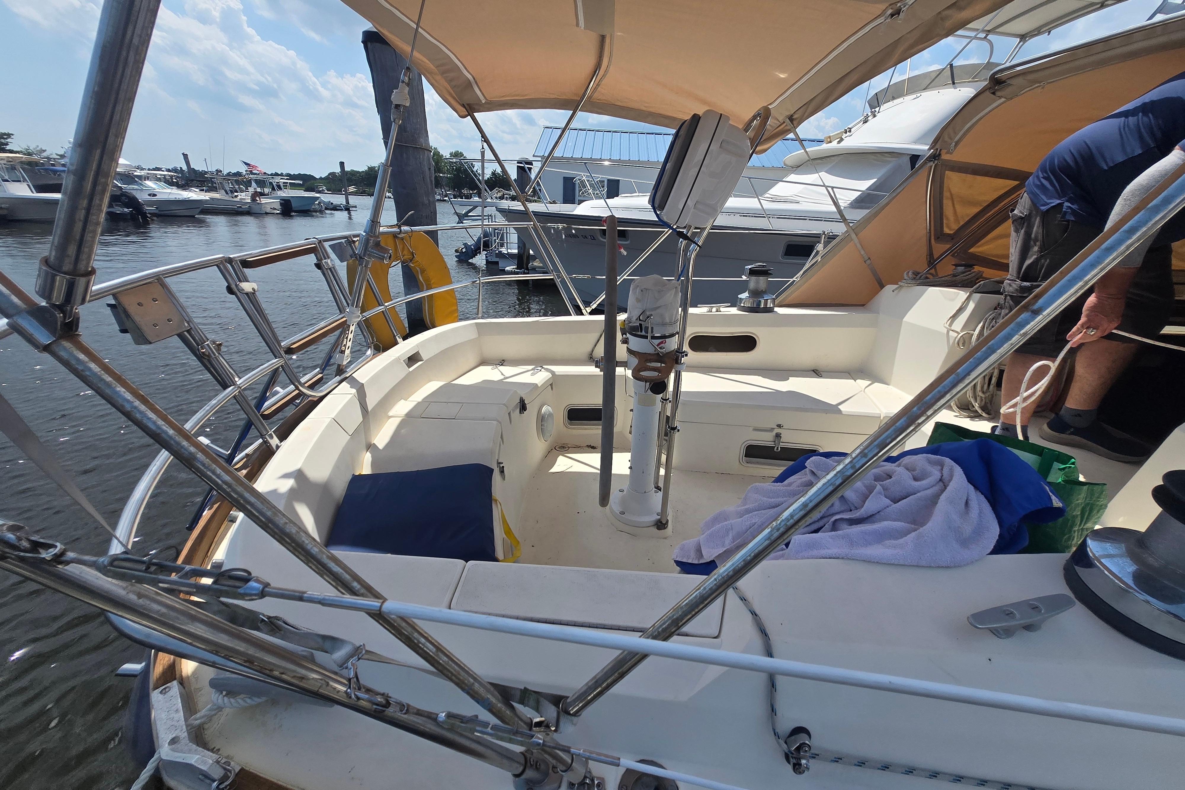 Cockpit of 1988 Sabre 38 sailboat docked at marina, featuring seating and canopy.