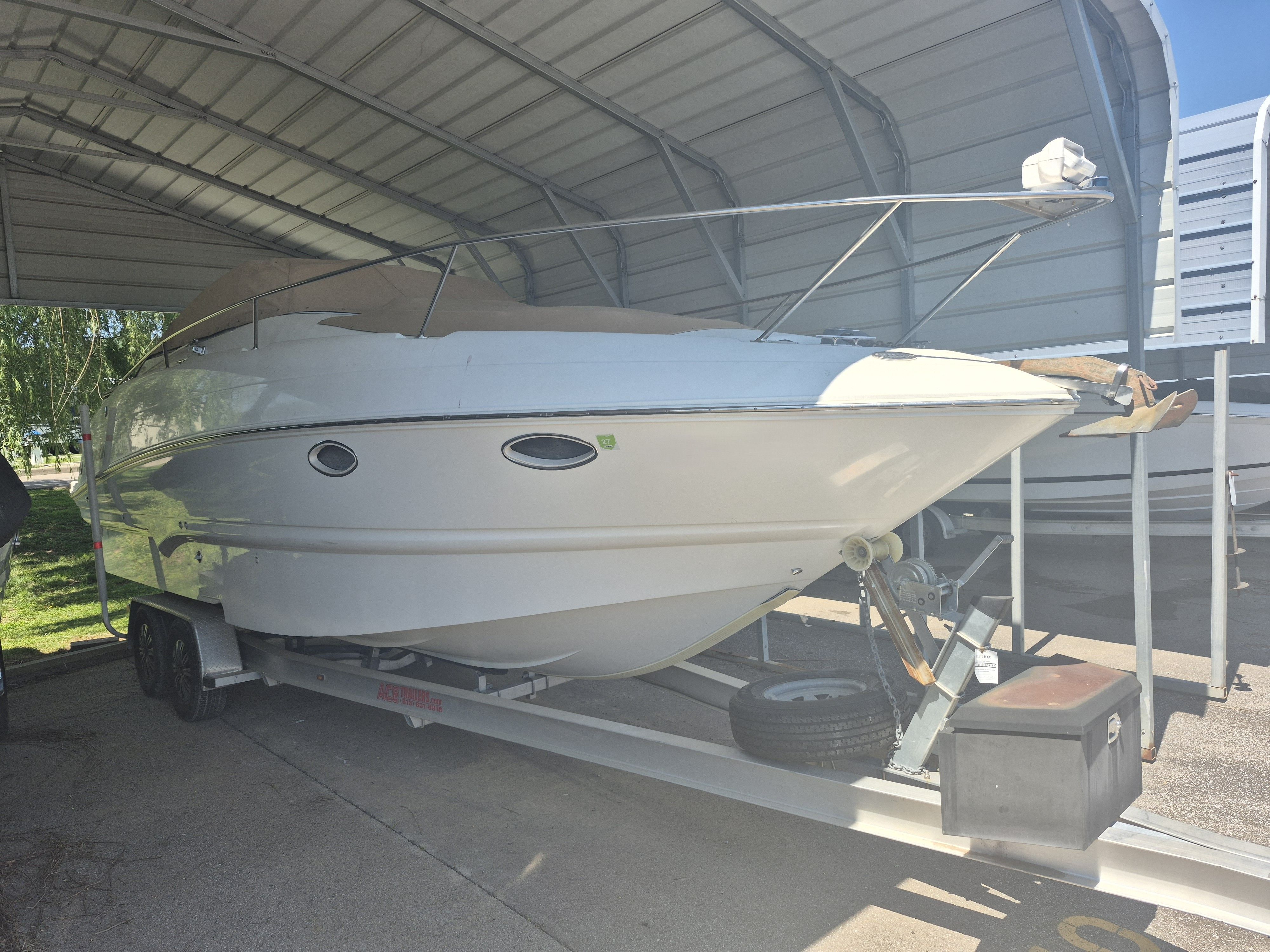 A white boat on a trailer in a covered area.