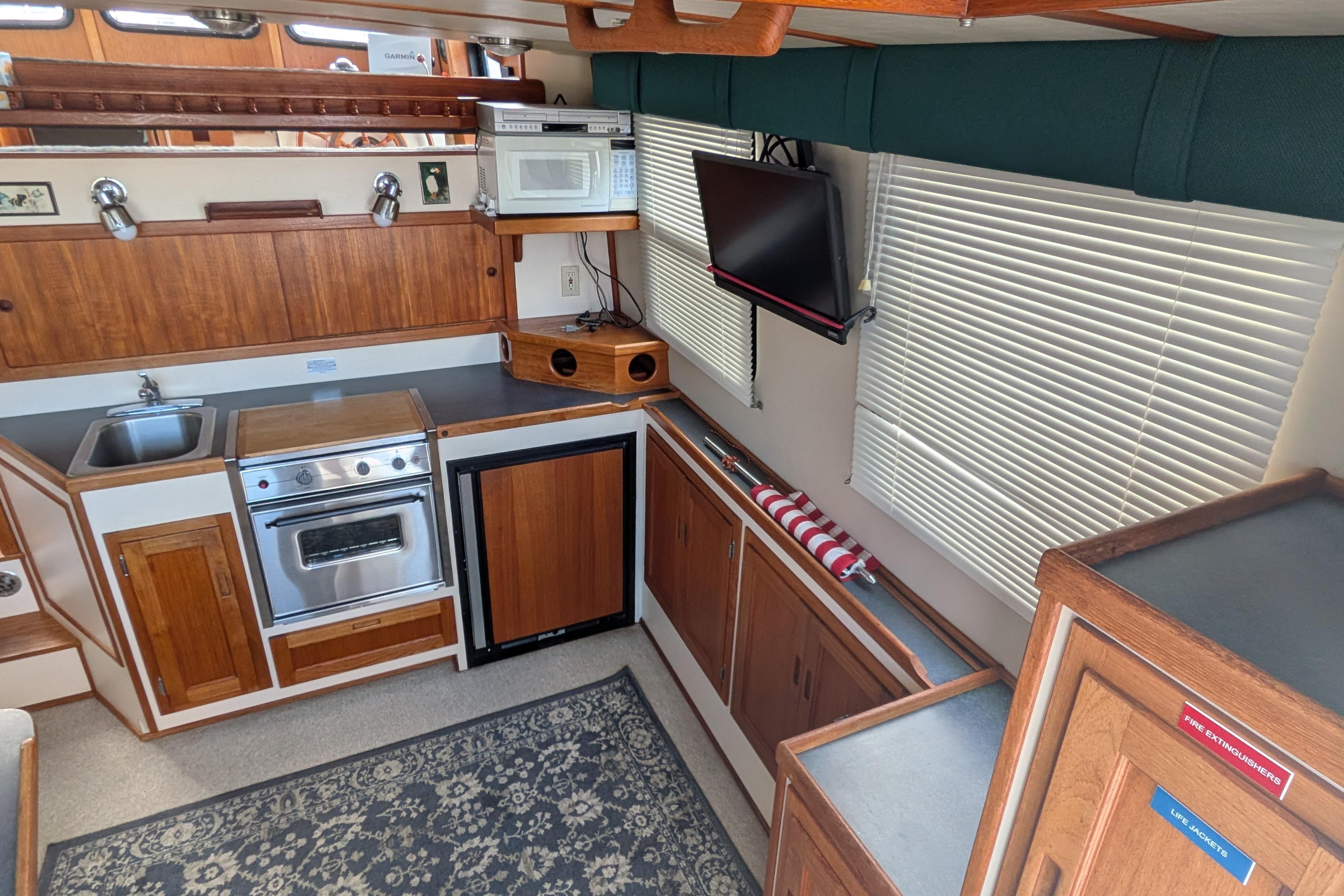 Interior of a 1998 Nordic Tug 32, featuring a compact kitchen with wood cabinetry.