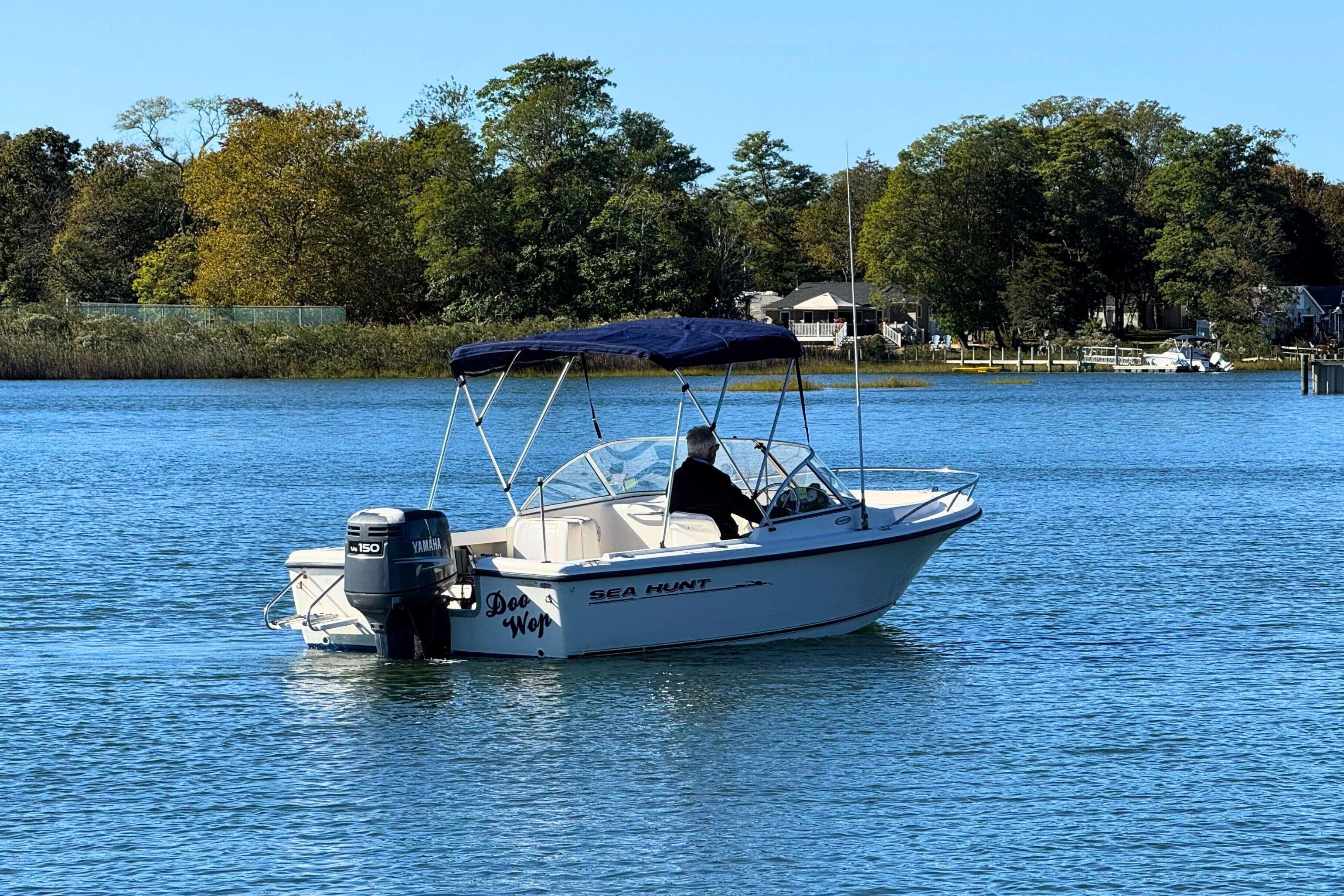 2002 Sea Hunt Escape 200 boat on calm water with trees in the background.