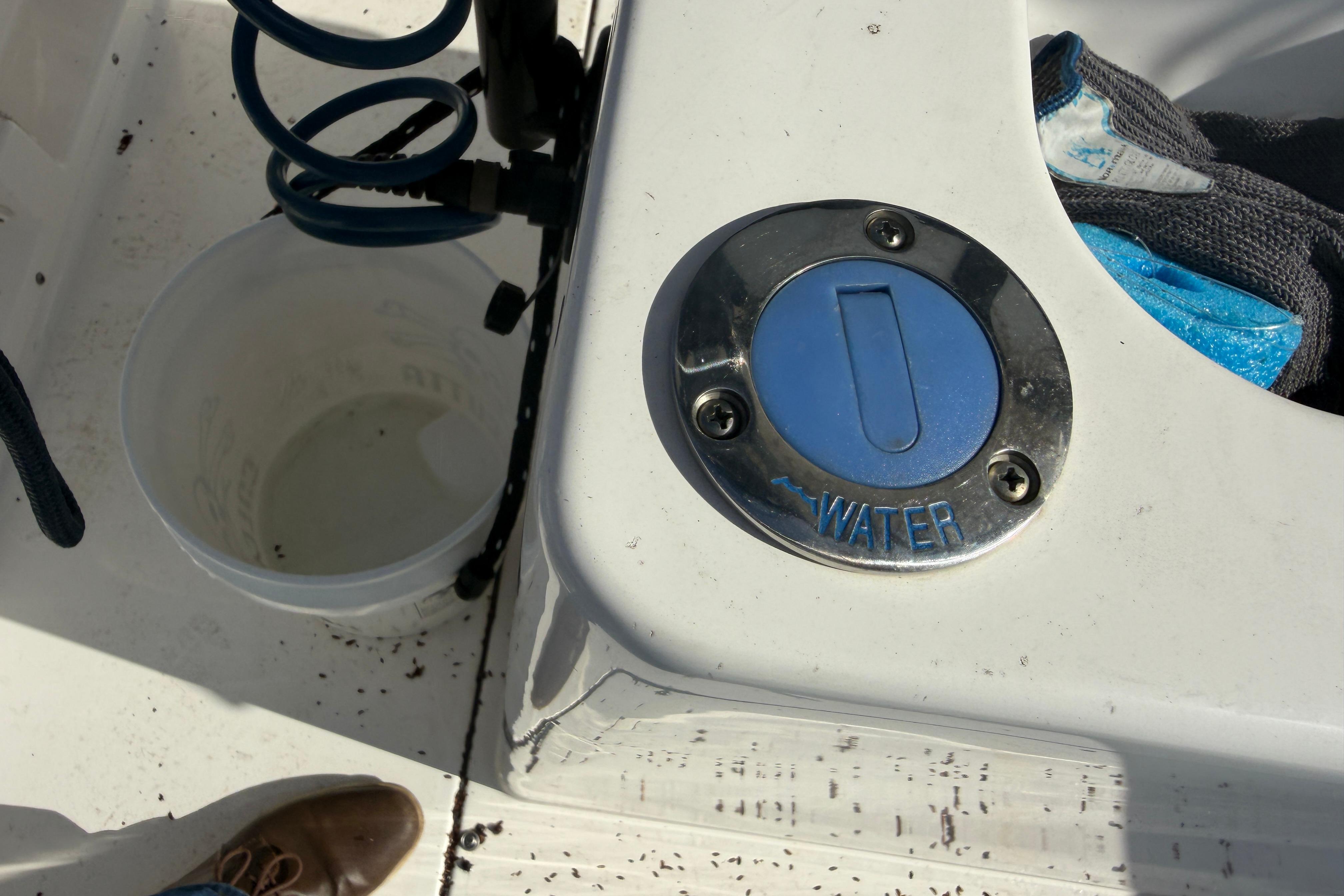 2024 Clearwater 2800 boat water fill cap with hose and bucket nearby.