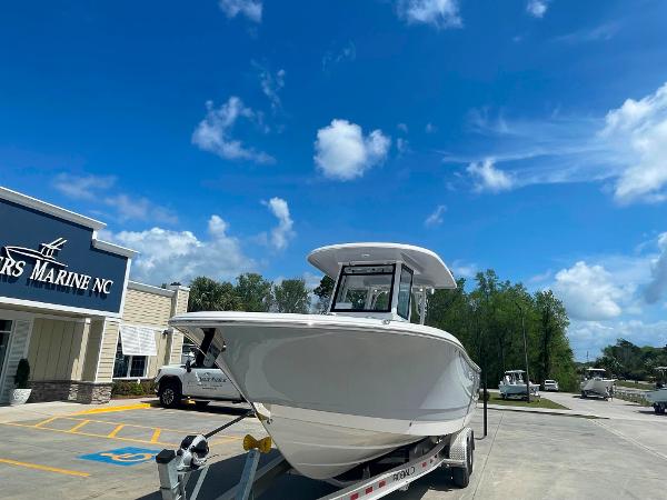 2023 Robalo R270 boat on trailer at dealership under blue sky.