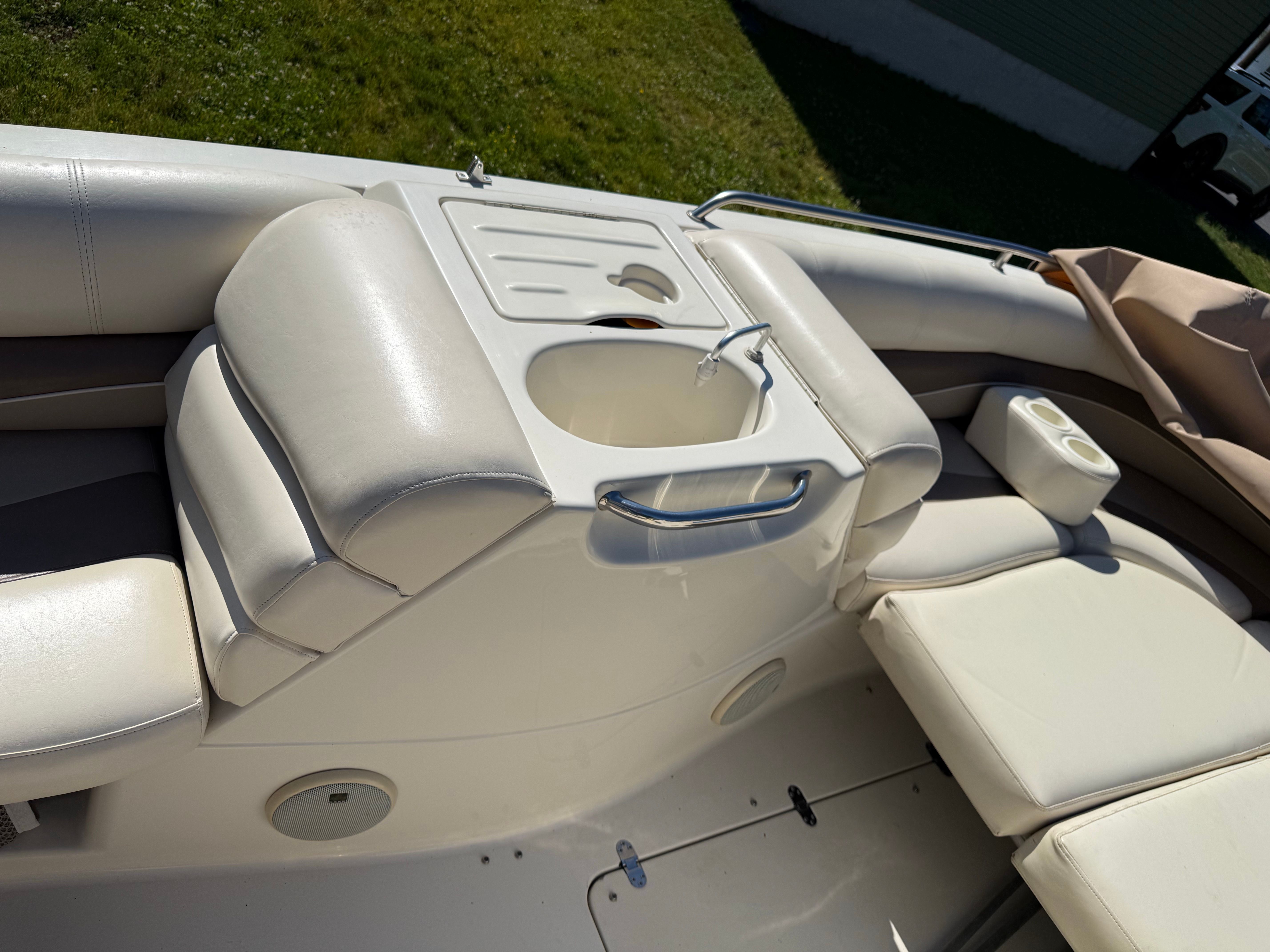 Interior of a Bennington RL210 boat with white upholstery and a sink.