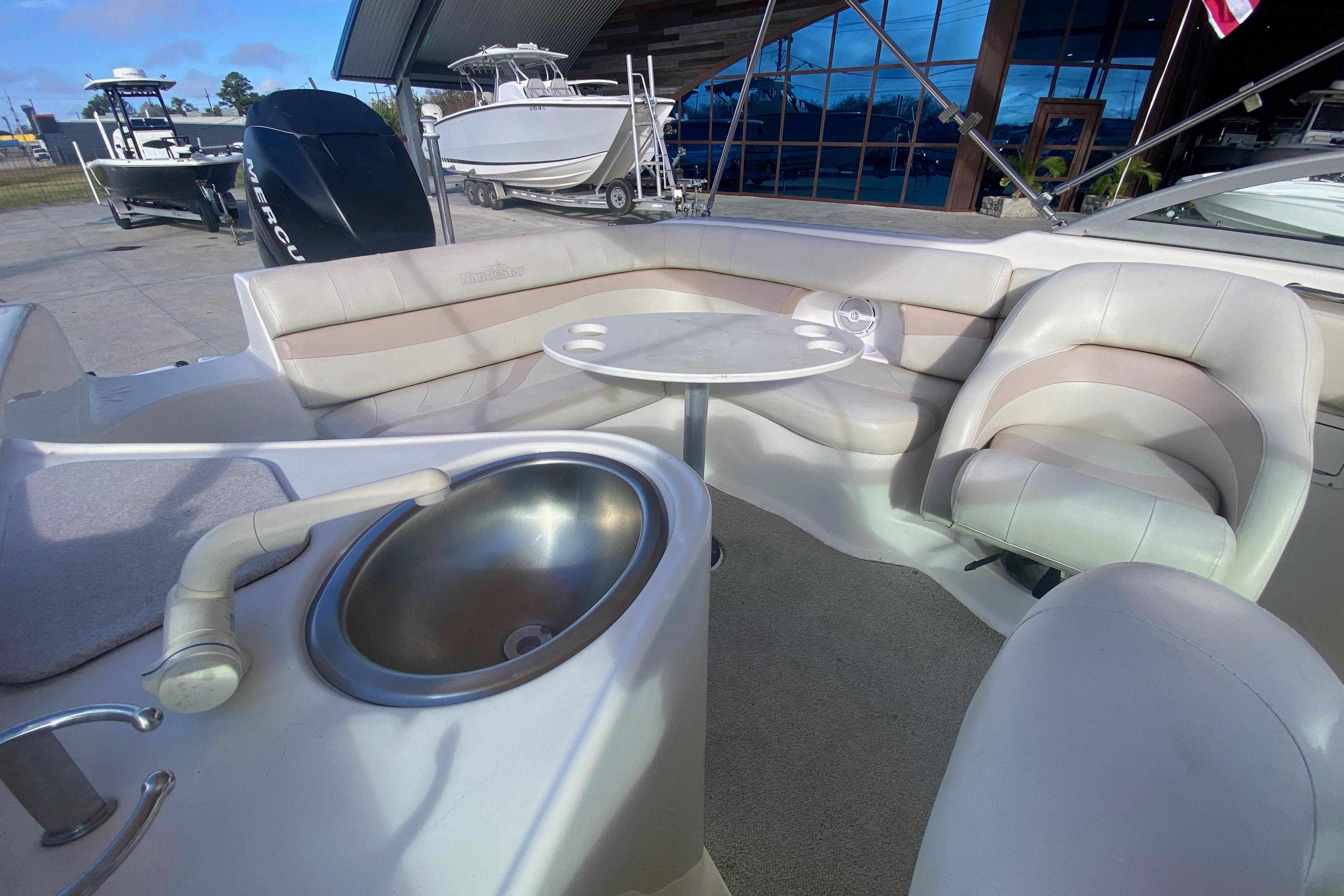 2007 NauticStar 230DC Sport Deck interior with seating, table, and sink.